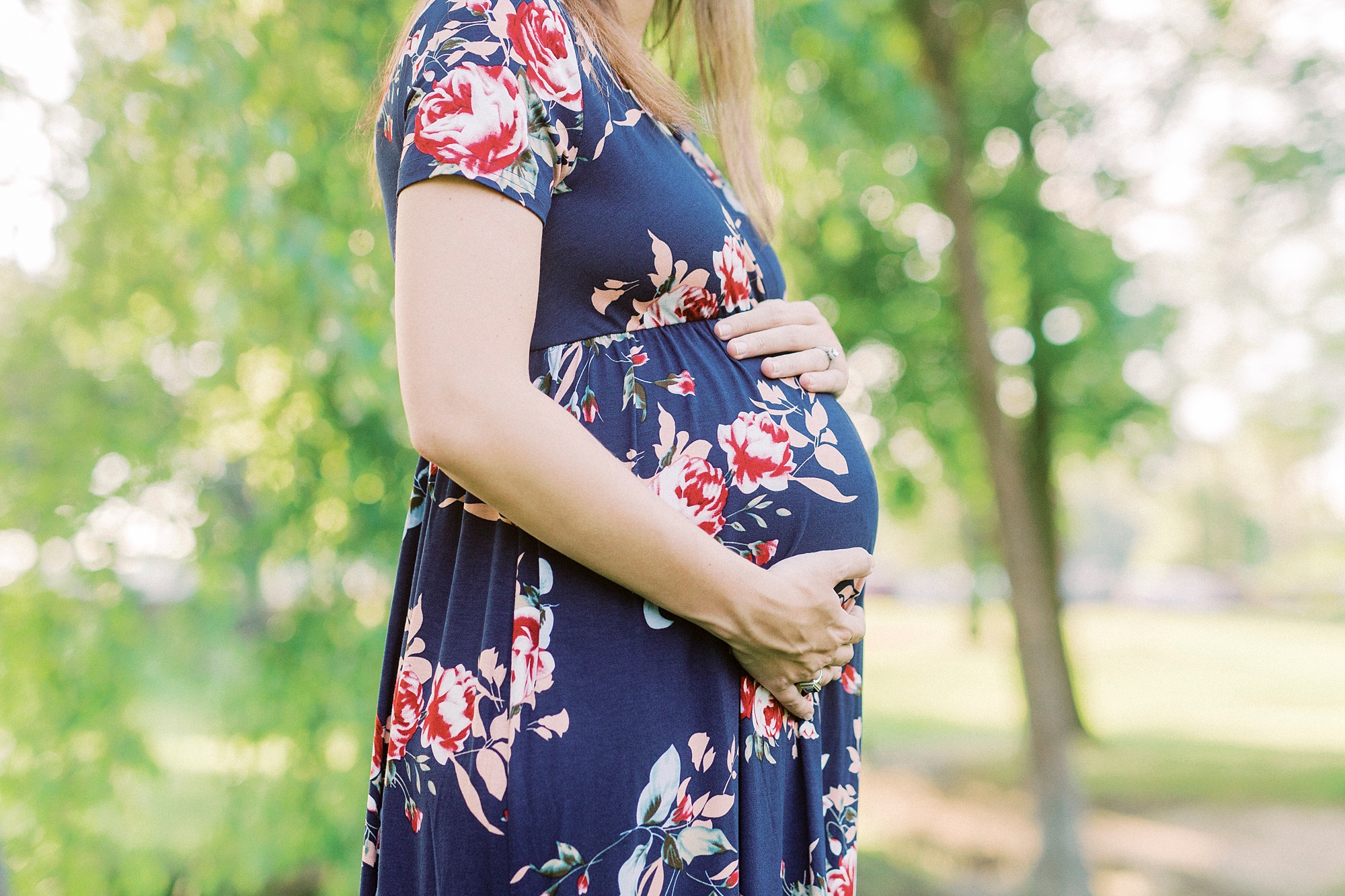woman holds belly during maternity photos in Rankin Lake Park