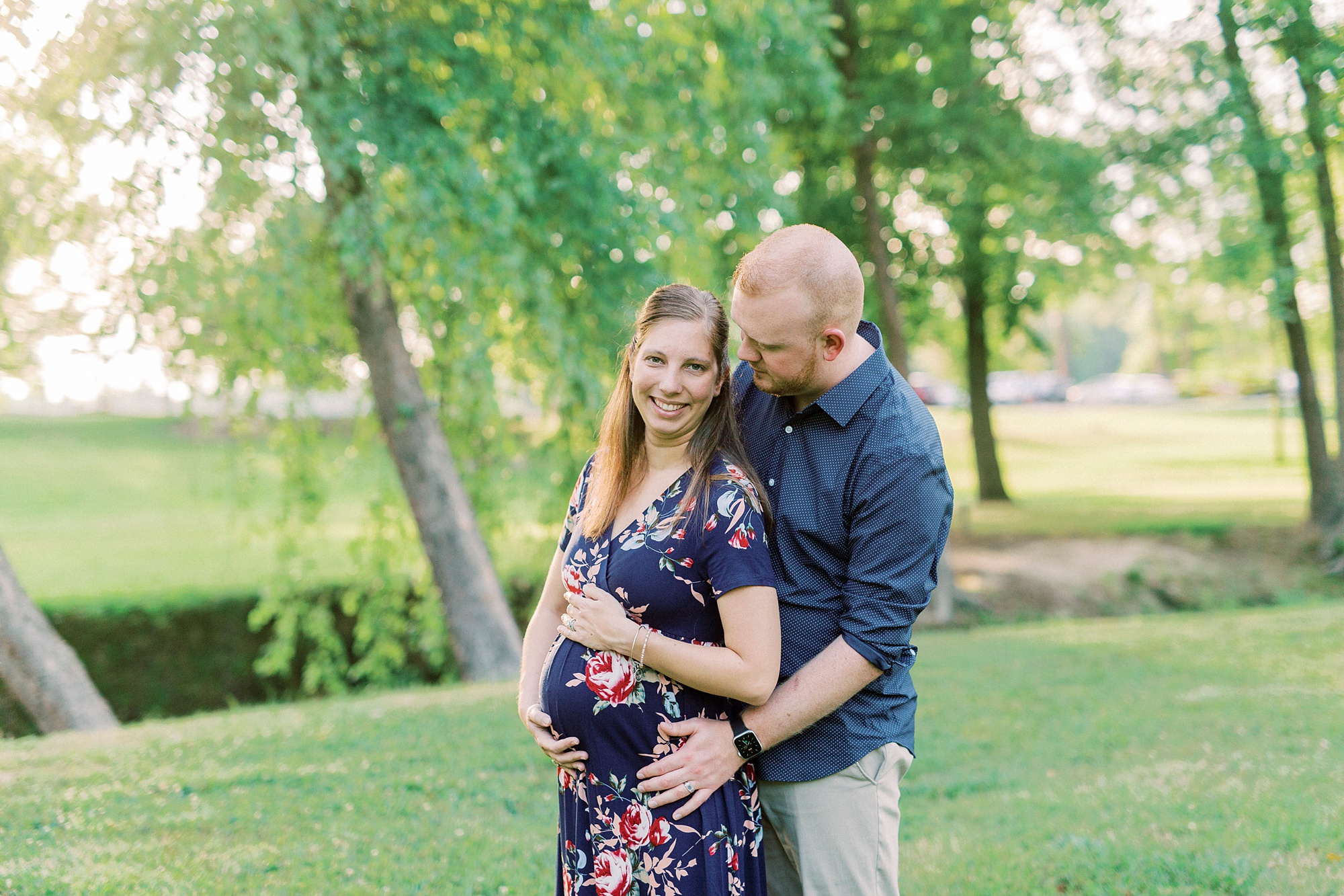 husband hugs wife from behind during maternity photos