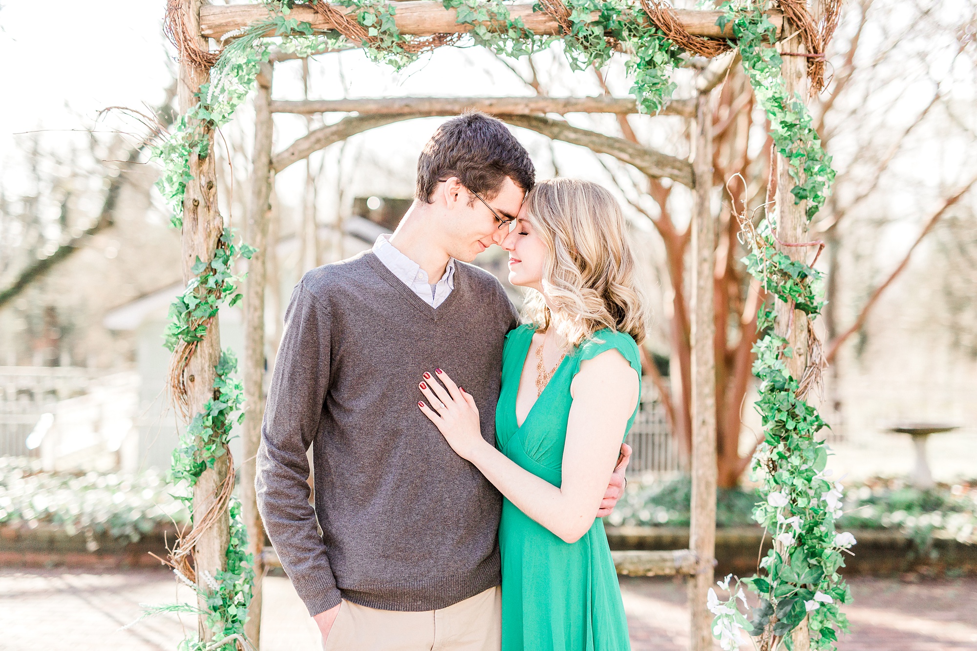 bride and groom touch foreheads by wooden arbor at 1812 Hitching Post