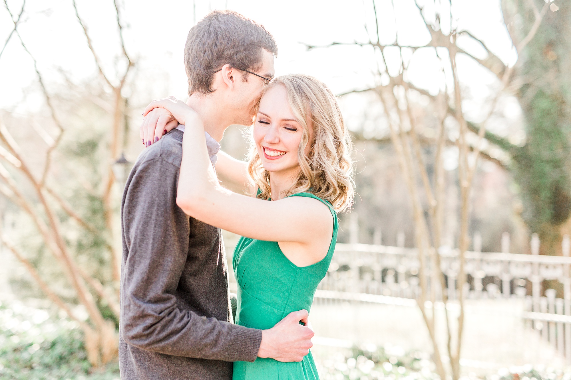 groom kisses bride's forehead with her arms around his neck
