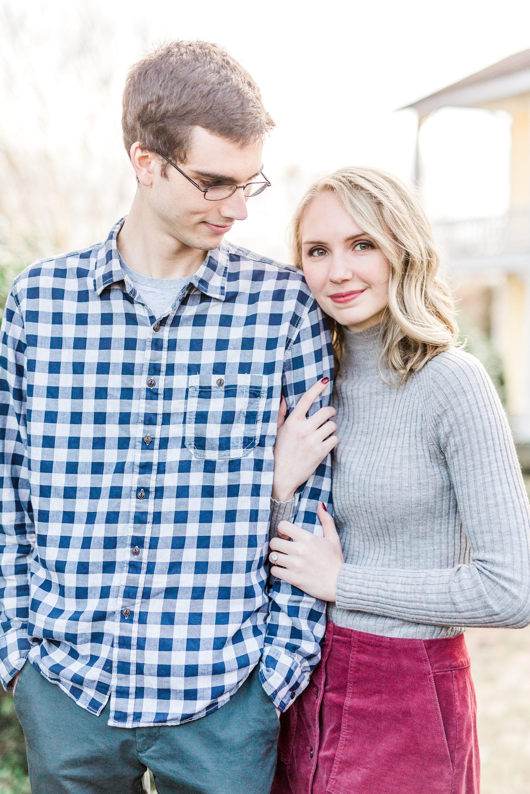 bride wraps hands around groom's arm during engagement session in NC