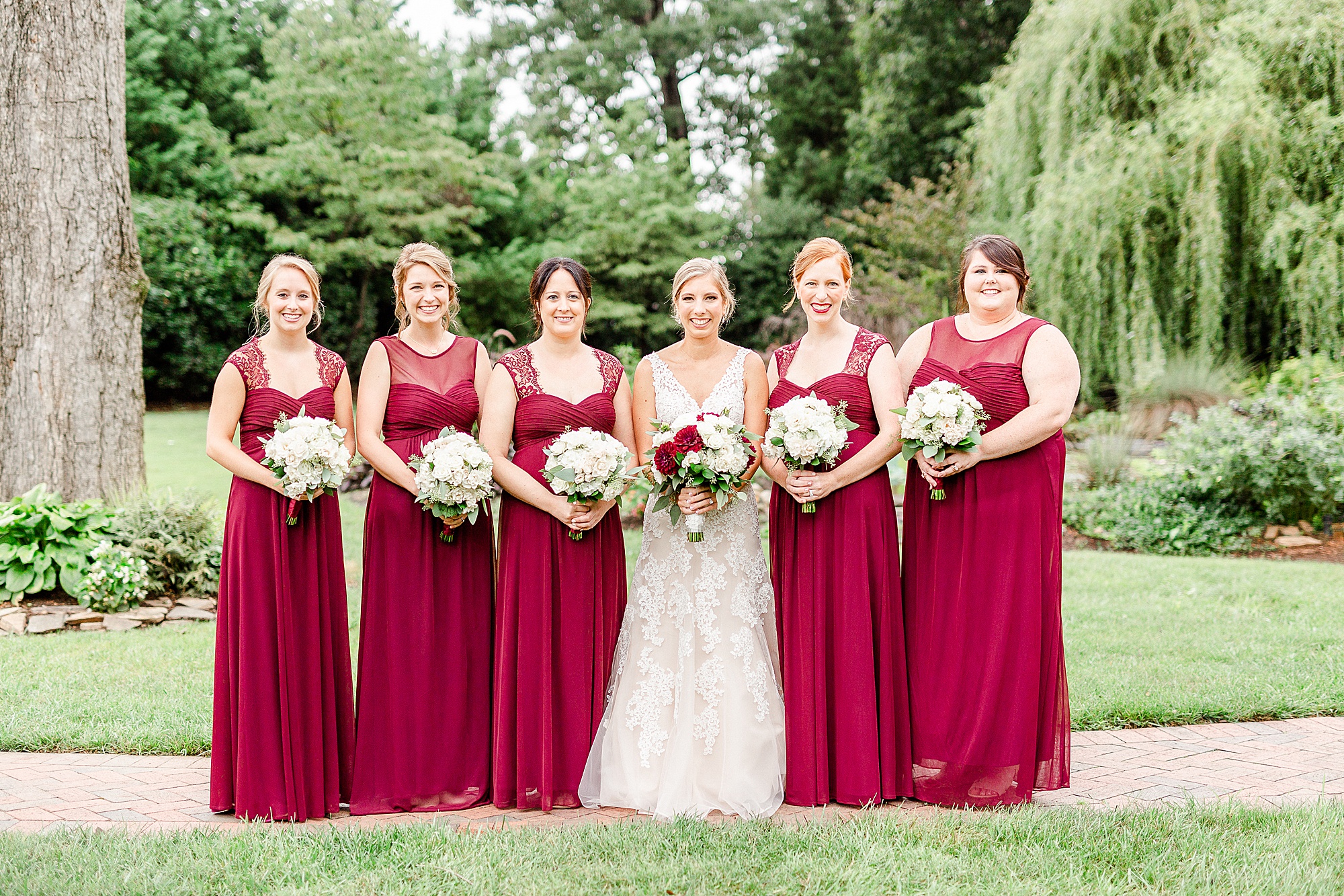 bride poses with five bridesmaids in red gowns