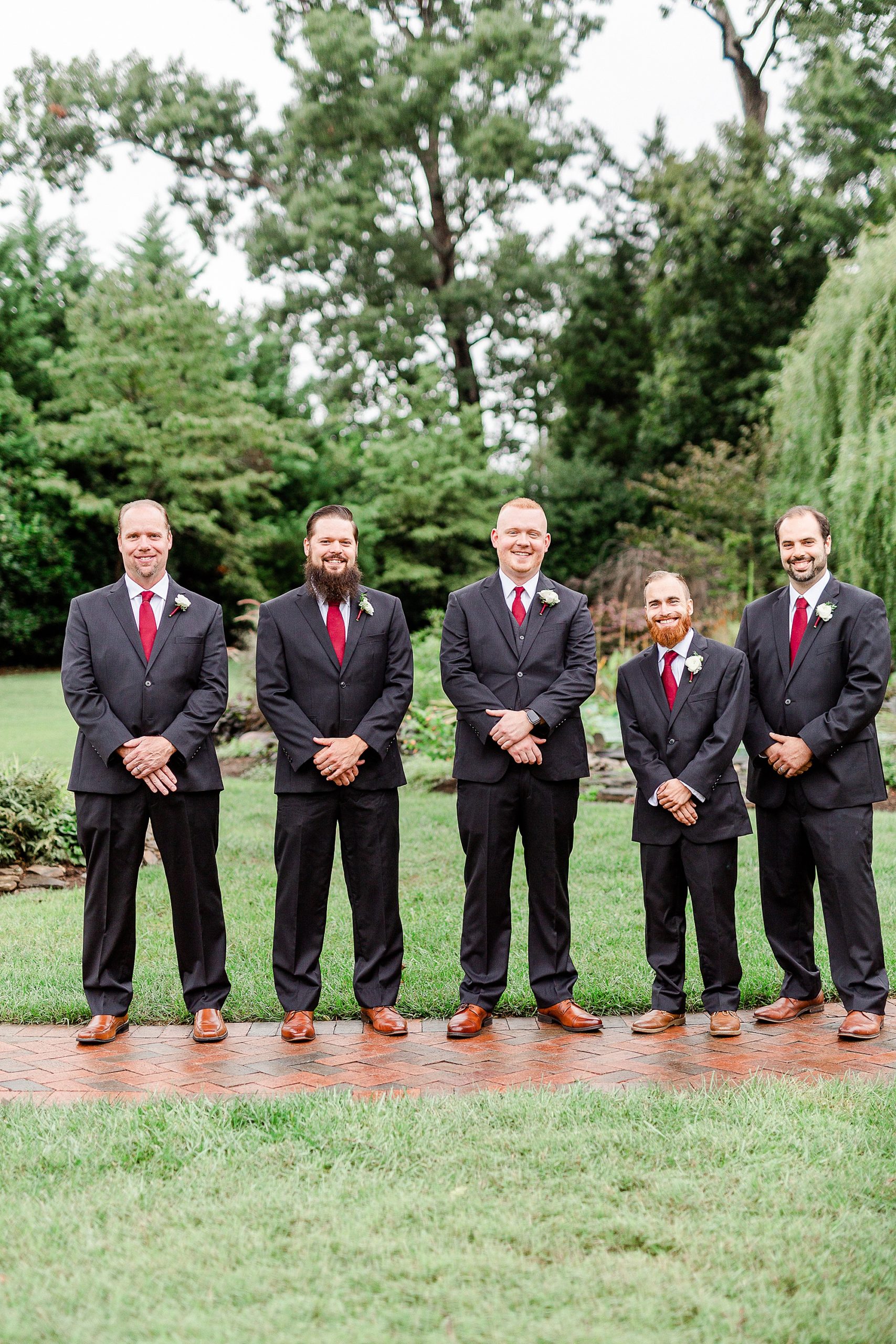 groom poses with groomsmen in suits at Alexander Homestead