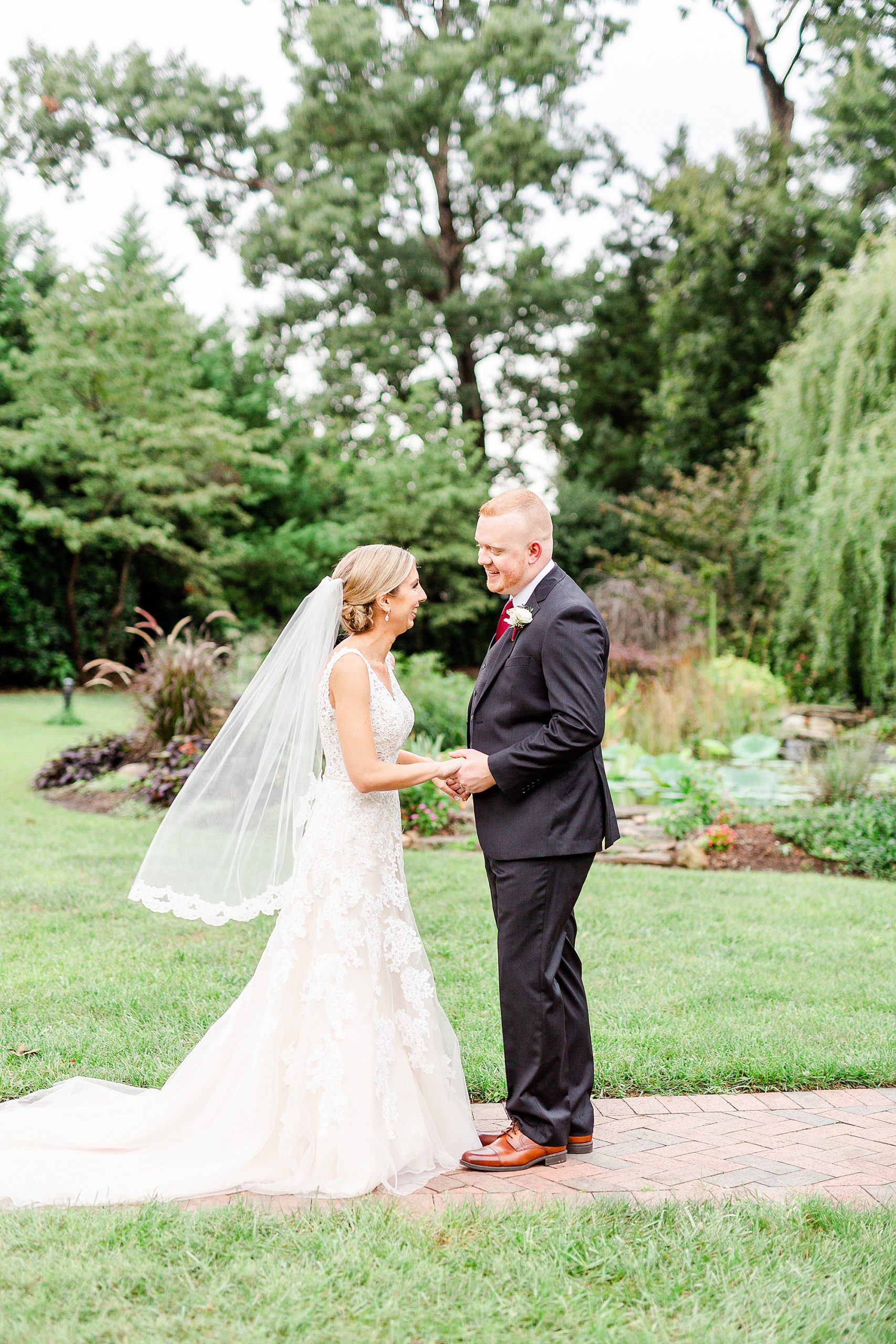 bride and groom hold hands looking at each other during wedding photos at Alexander Homestead