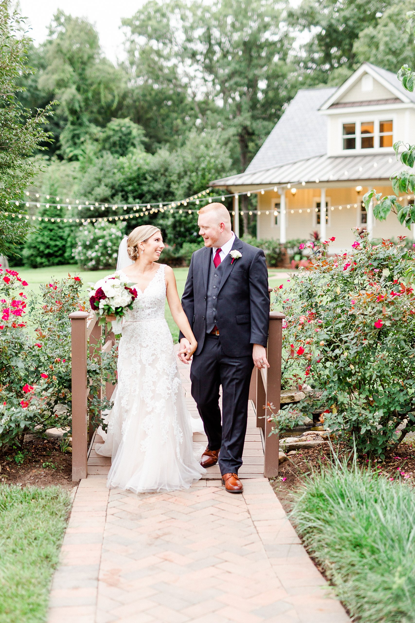 newlyweds walk over bridge in Alexander Homestead
