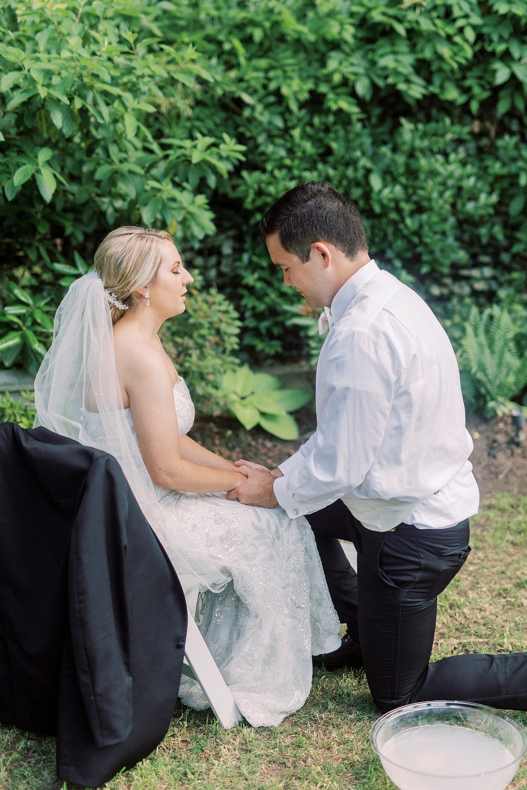 bride and groom hold hands during foot washing ceremony