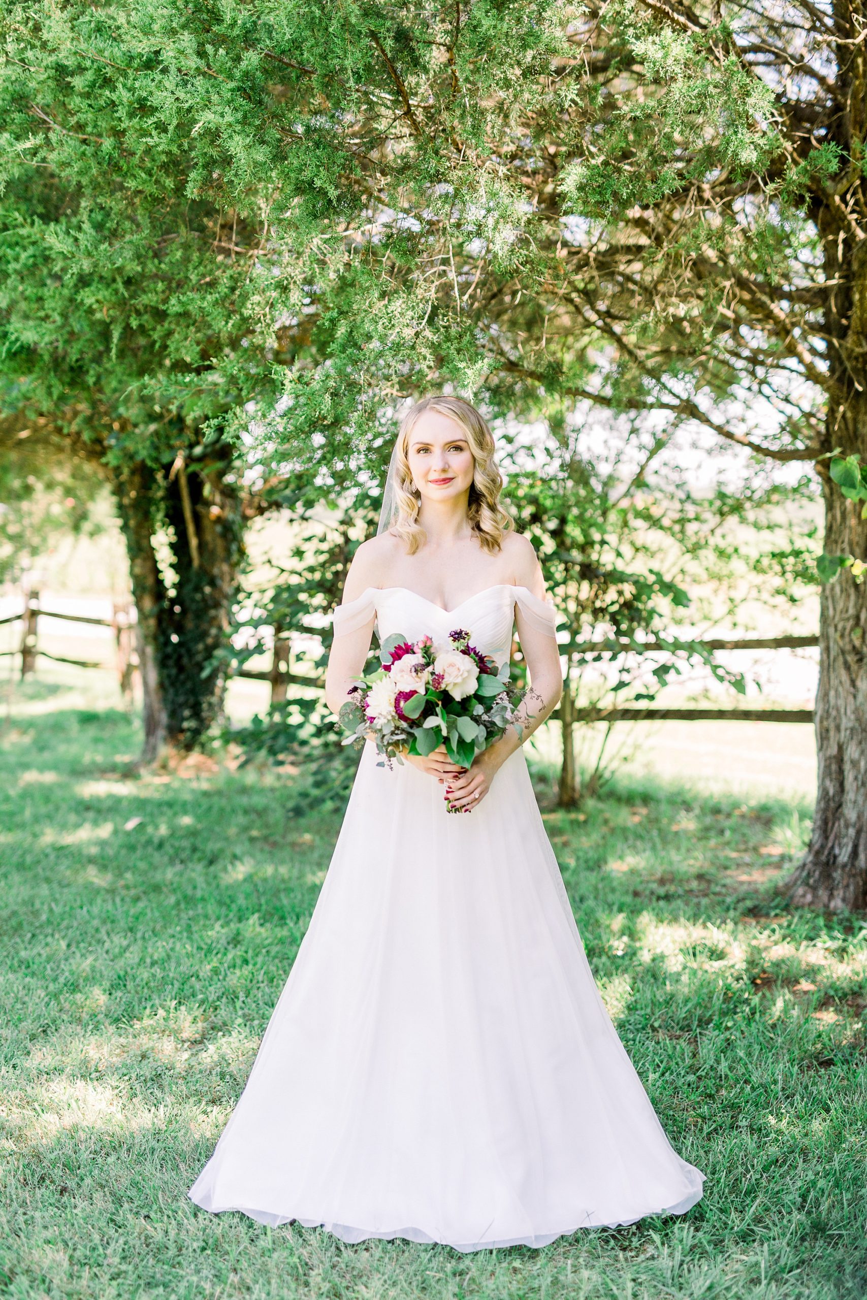 bride poses under trees during bridal portraits at 1812 Hitching Post