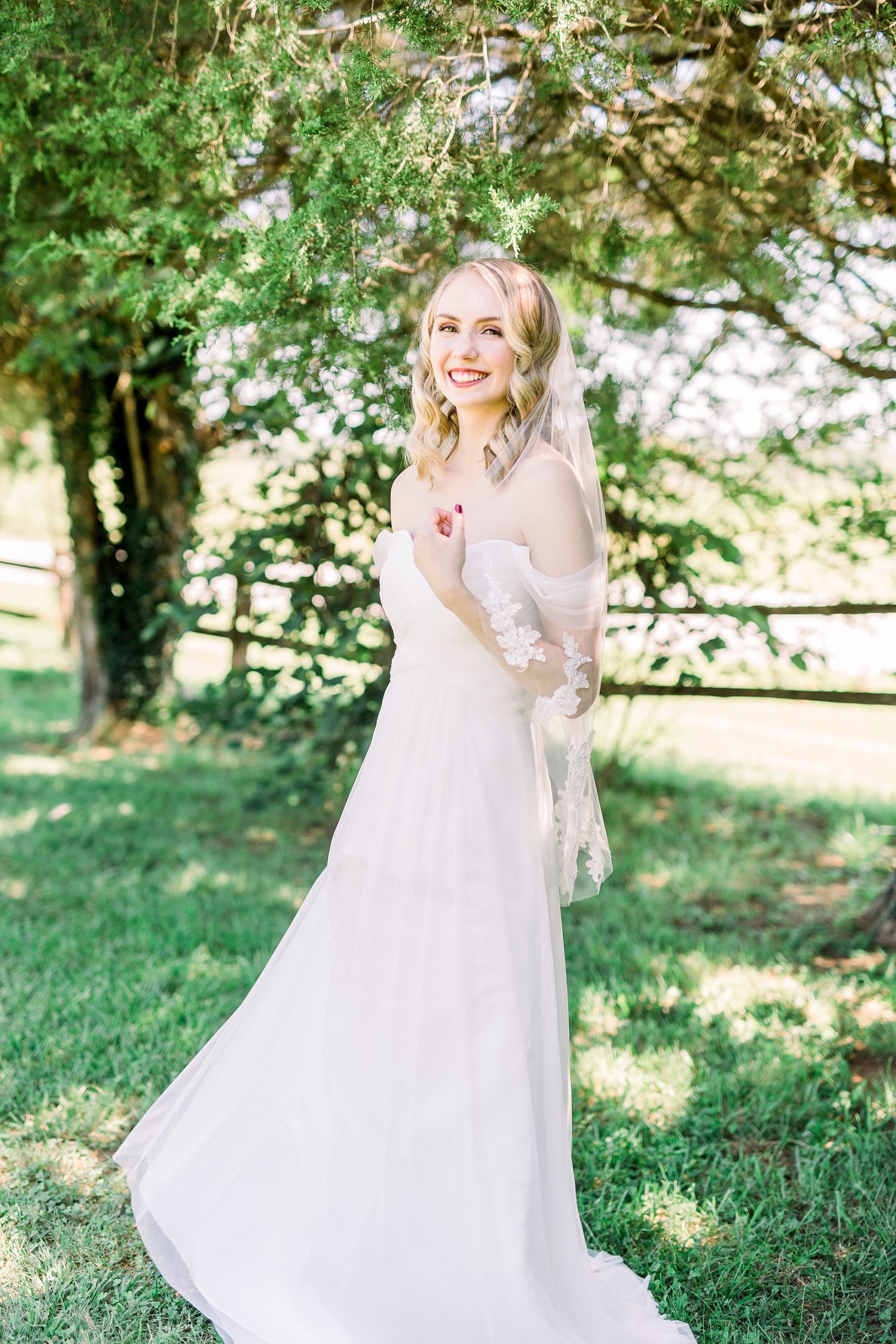 bride smiles holding hair during NC wedding portraits