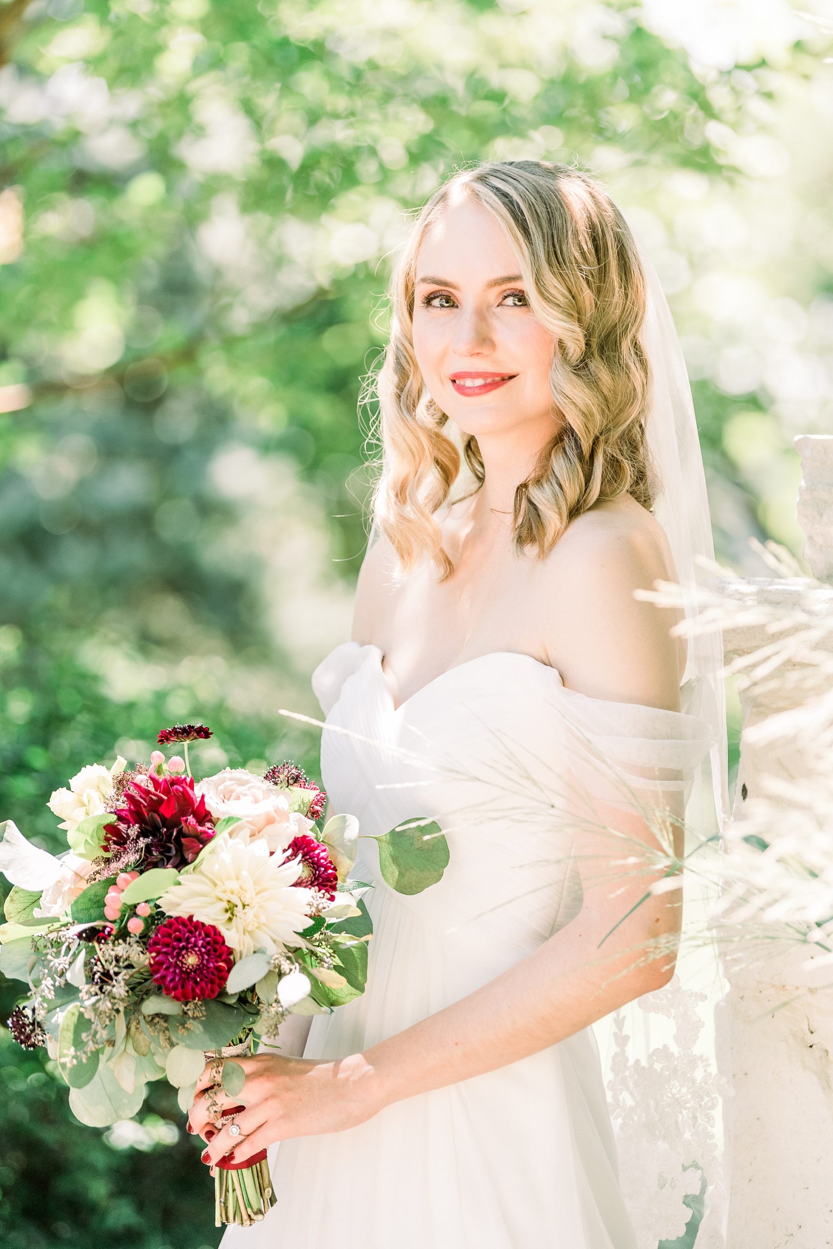 bride poses by fence during portraits at 1812 Hitching Post