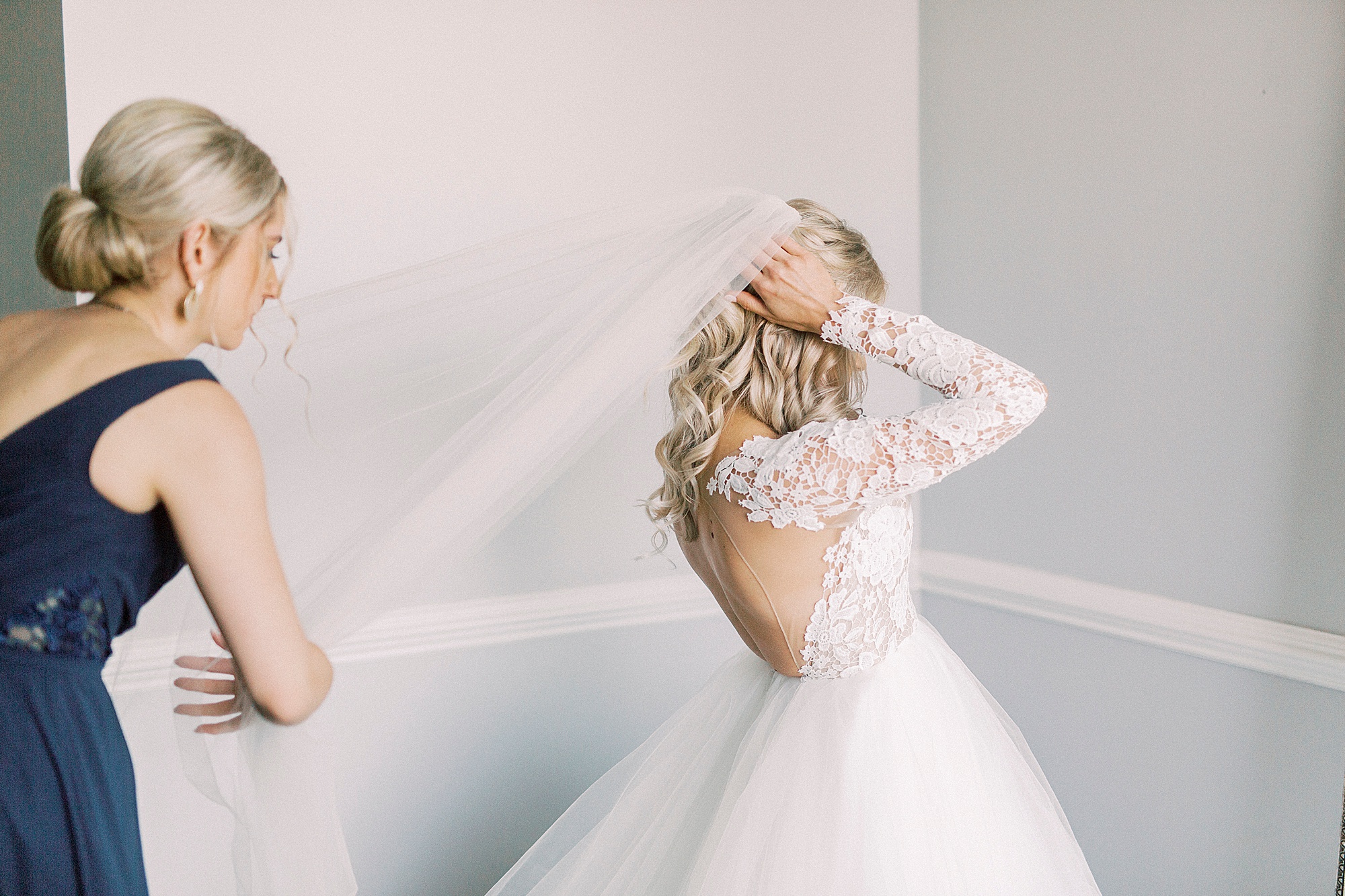 bridesmaid helps bride with veil over Hayden Olivia bridal gown