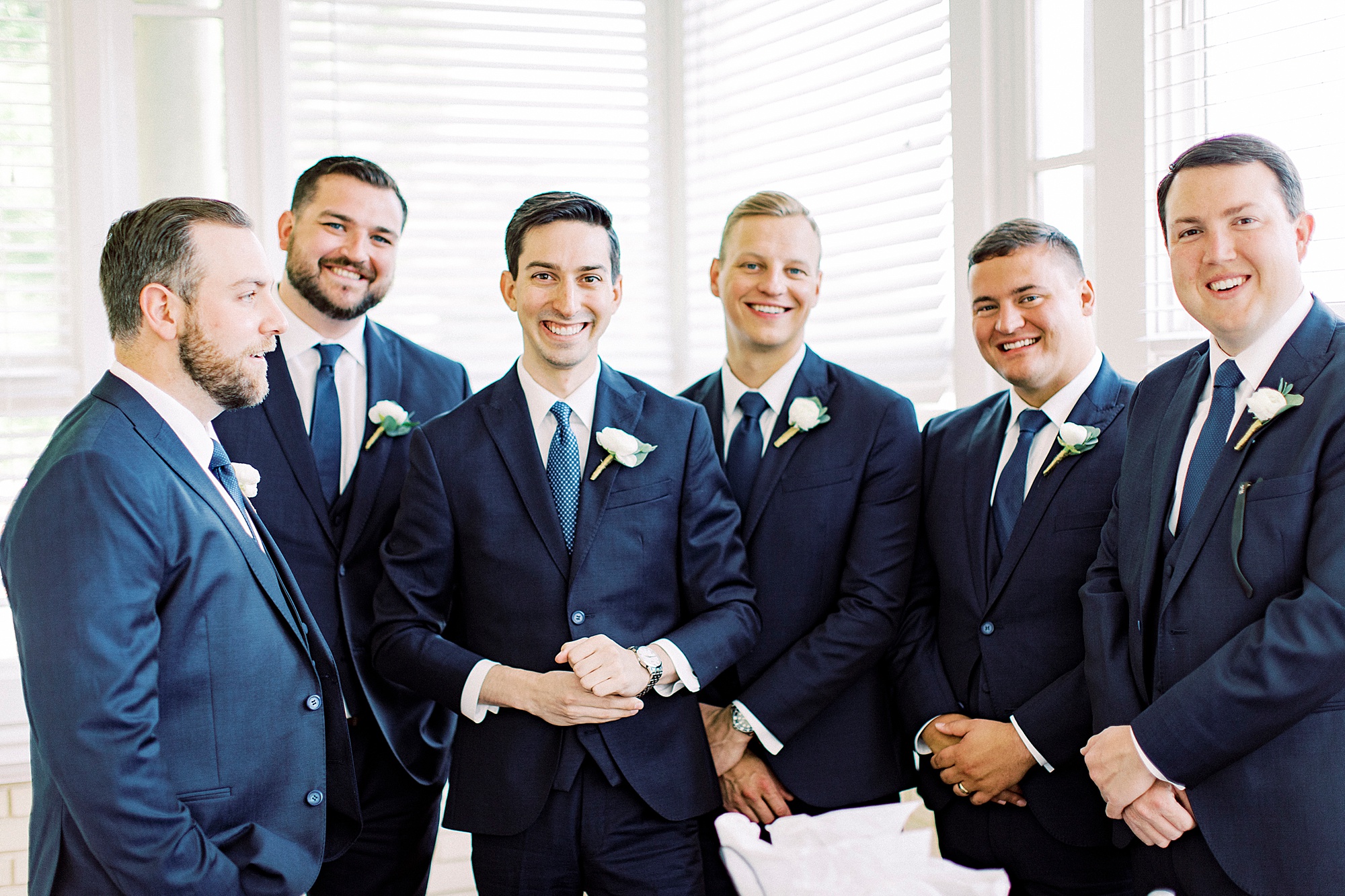 groom and groomsmen in navy suits pose along wall at Separk Mansion