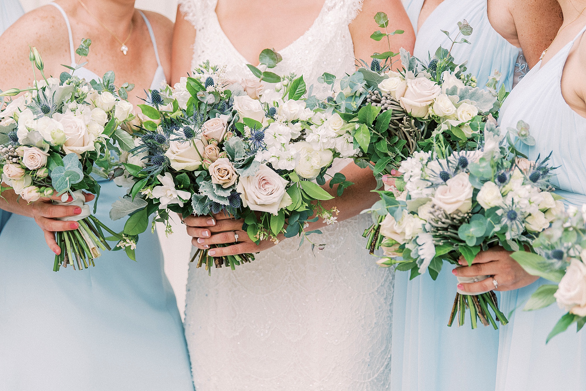 bride and bridesmaids hold bouquet with ivory flowers