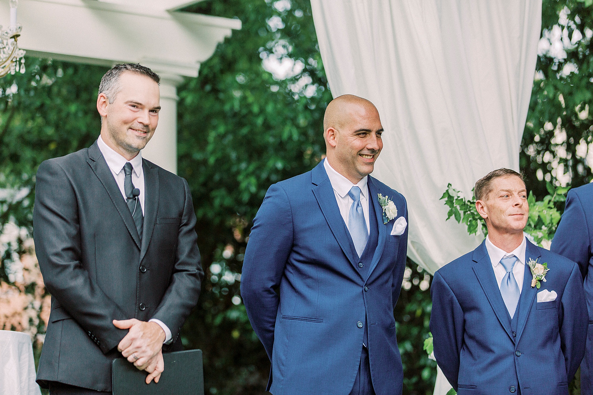 groom smiles watching bride walk down aisle