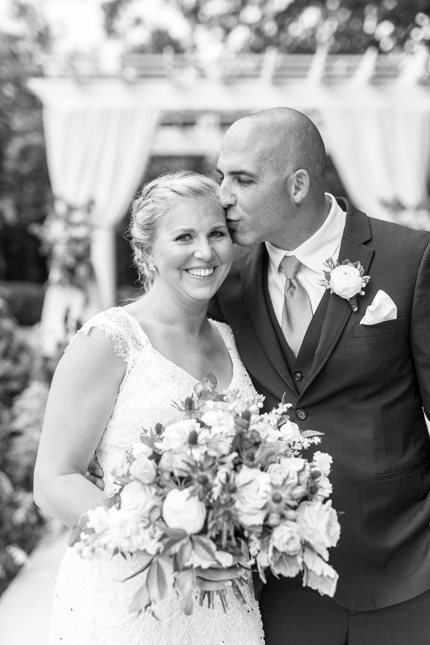 groom kisses bride's forehead during photos