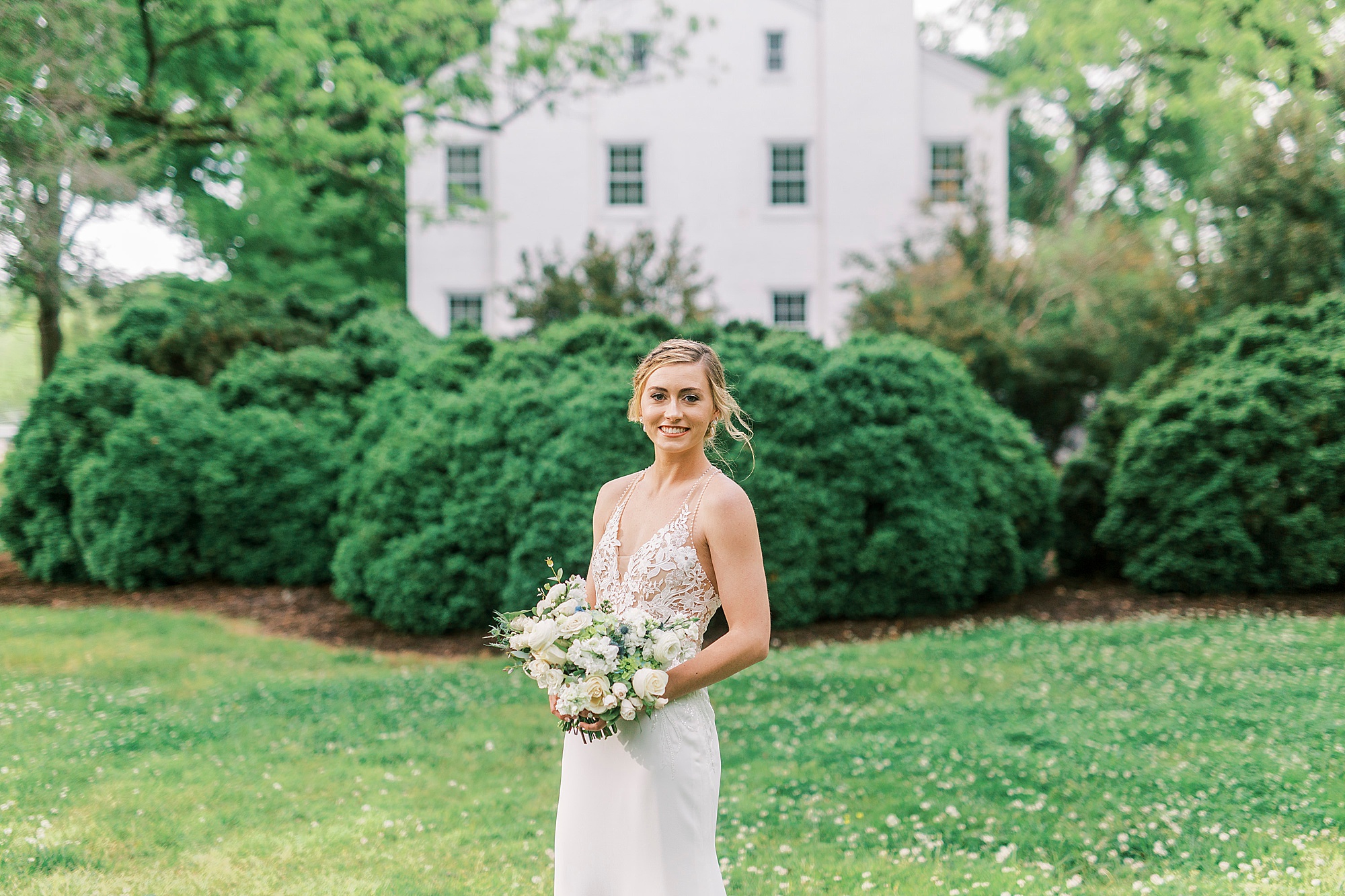 bride holds bouquet in front of bushes at Tanglewood Park