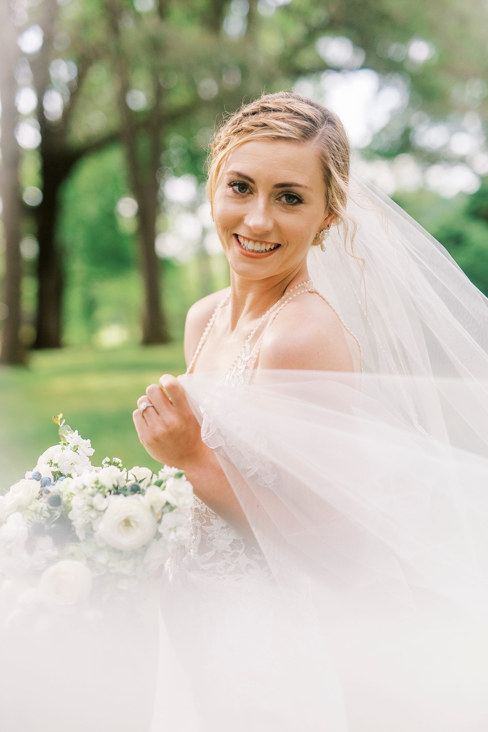 bride holds veil around shoulders during spring bridal session