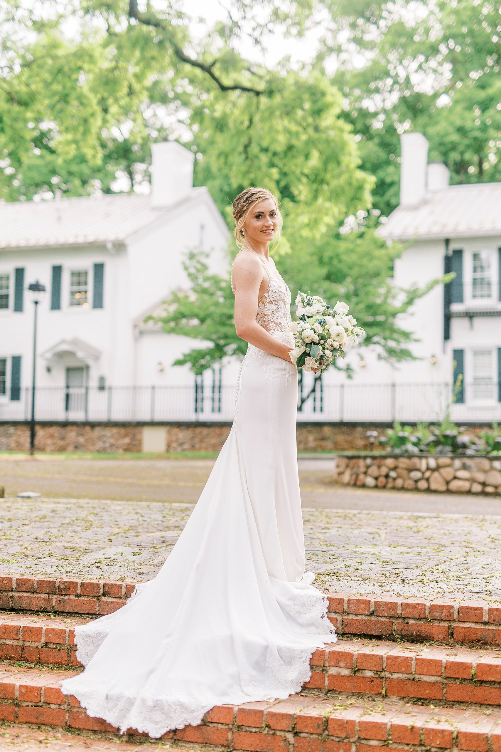 bride stands on steps at Tanglewood Park looking over shoulder