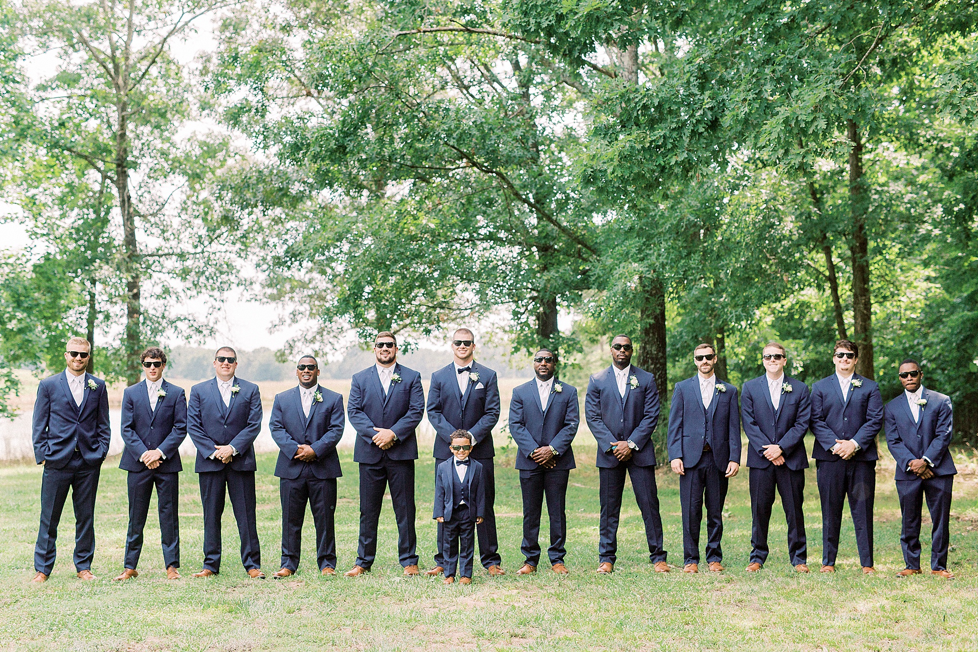groom poses with groomsmen in navy suits
