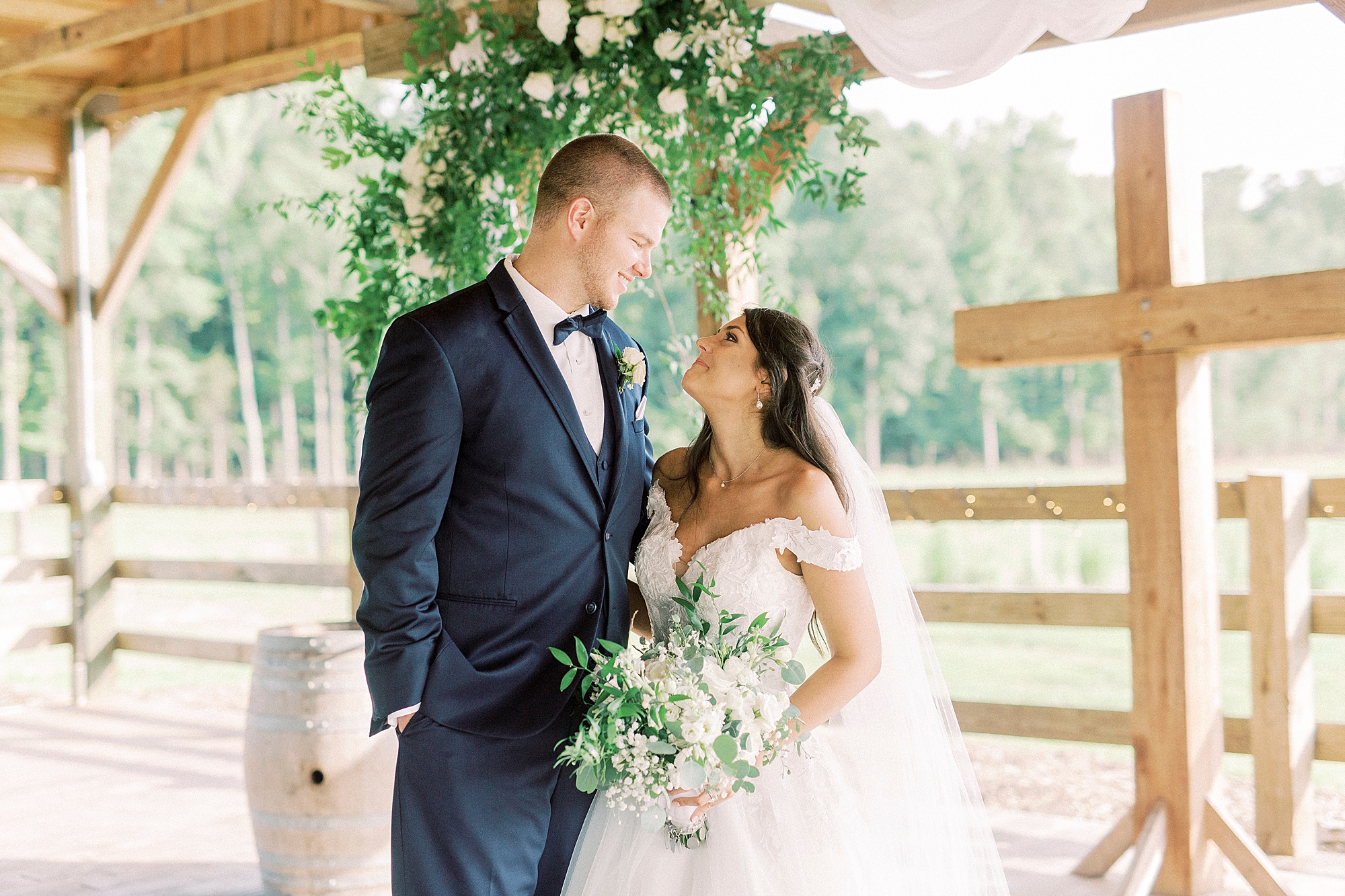 newlyweds pose by wooden cross
