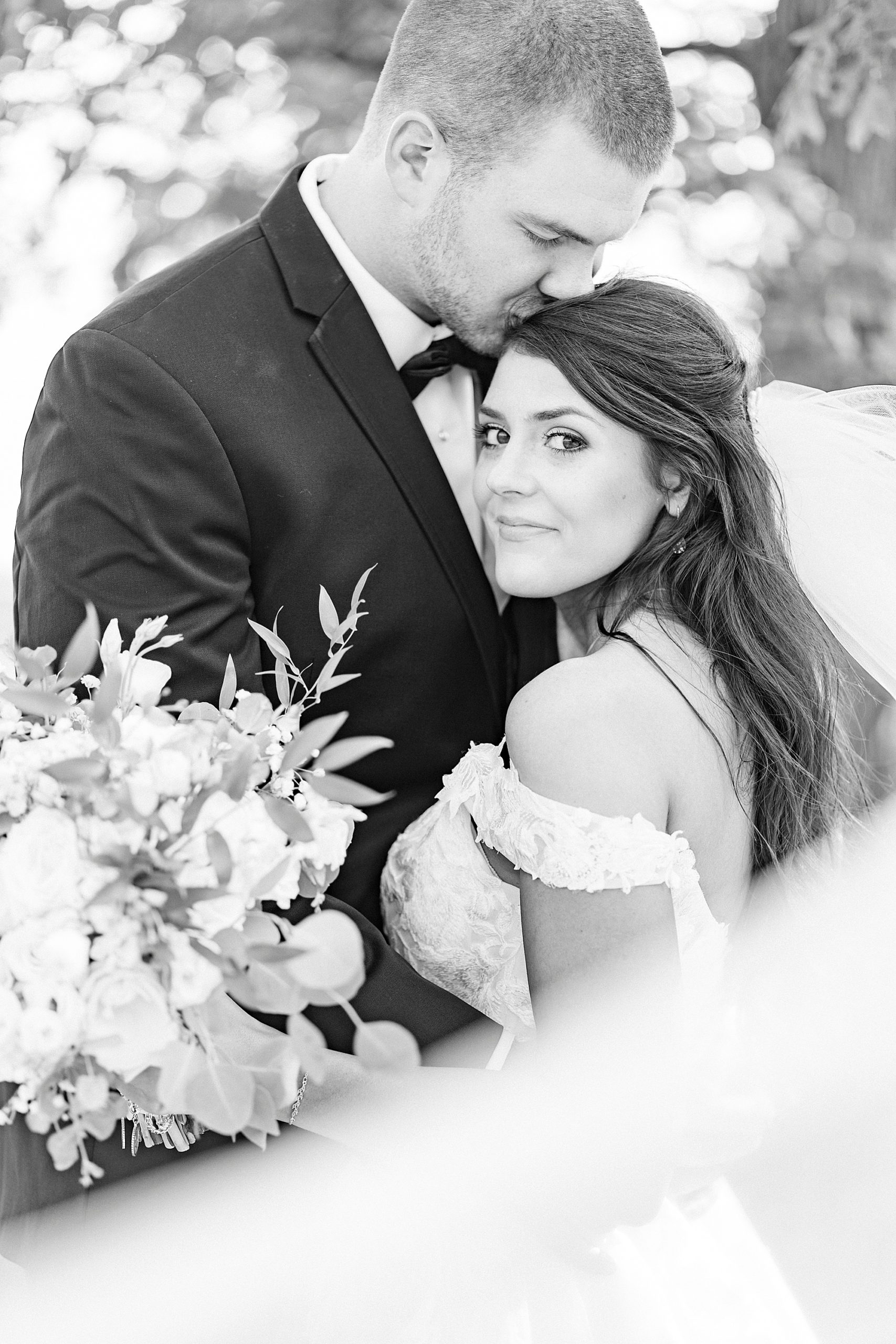 groom kisses bride's head during wedding photos