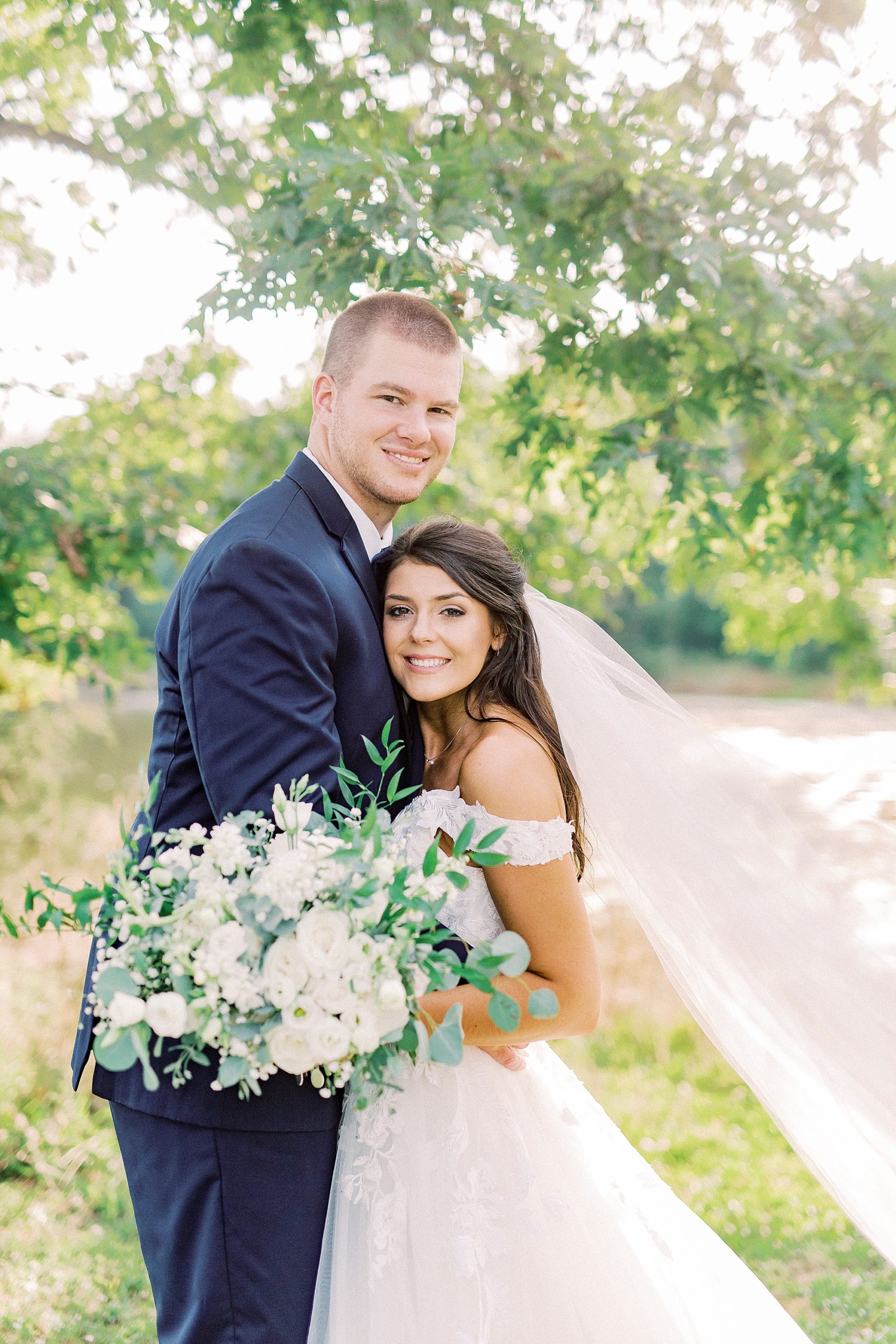 newlyweds hug in field at The Farmstead