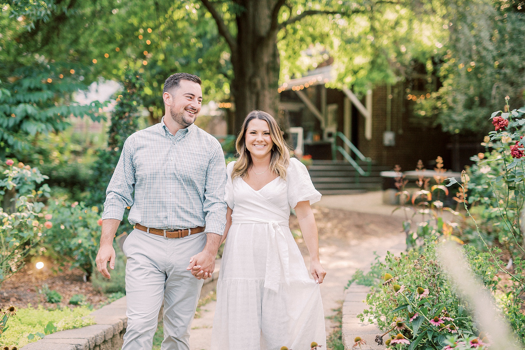 engaged couple holds hands walking through McGill Rose Garden