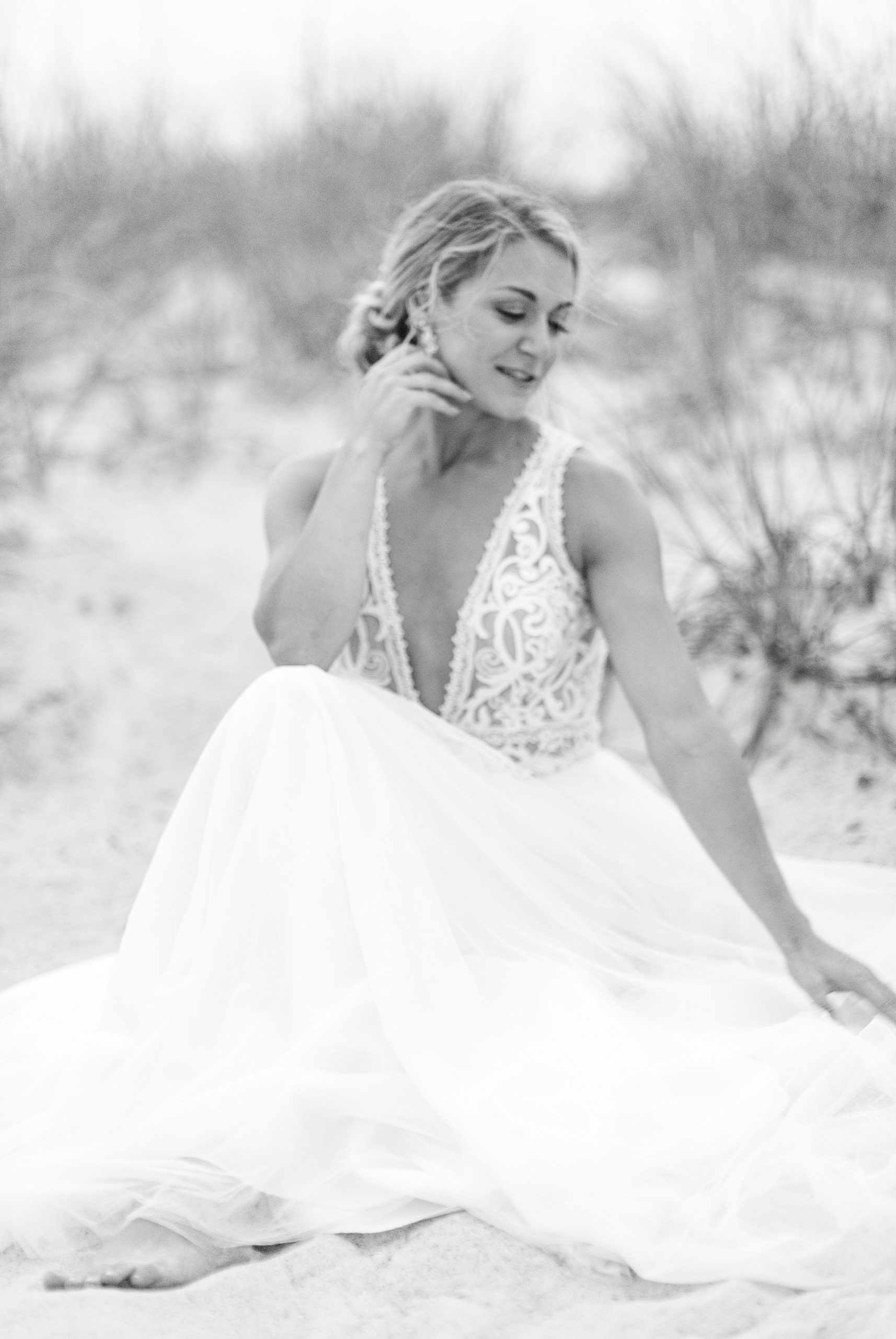 bride sits on sand looking over shoulder