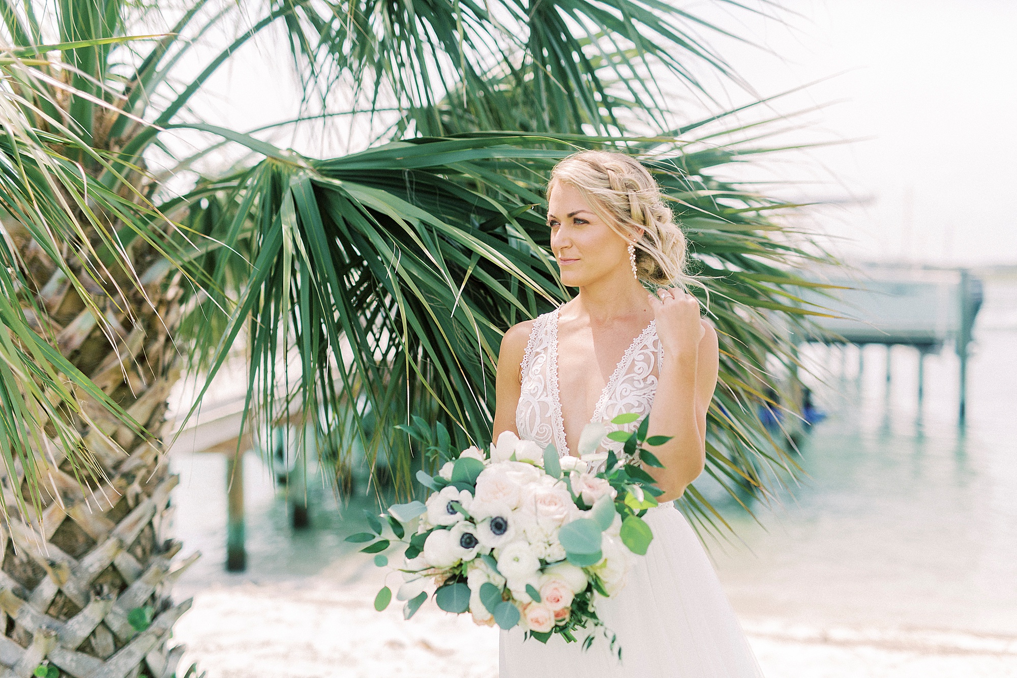 bride holds bouquet posing by palm trees in Wilmington NC