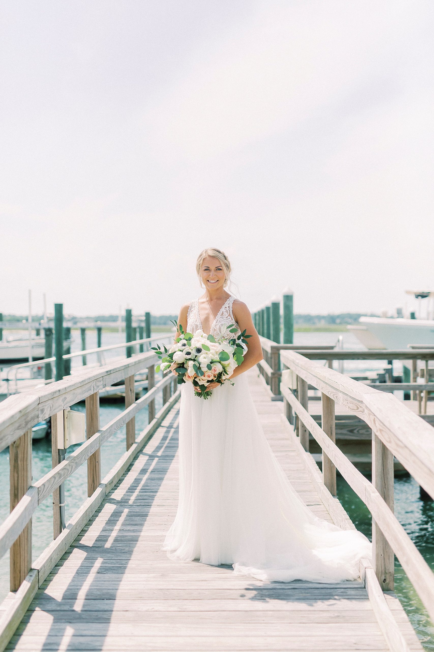 bride poses on pier at Wrightsville Beach