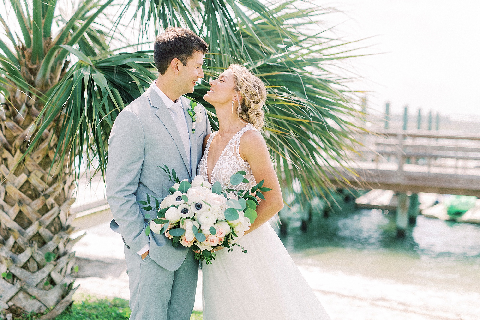 bride and groom look at each other by palm tree before Oceanic Restaurant wedding