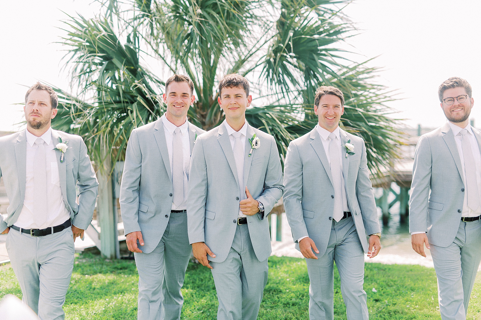 groom walks with groomsmen by pie at Wrightsville beach