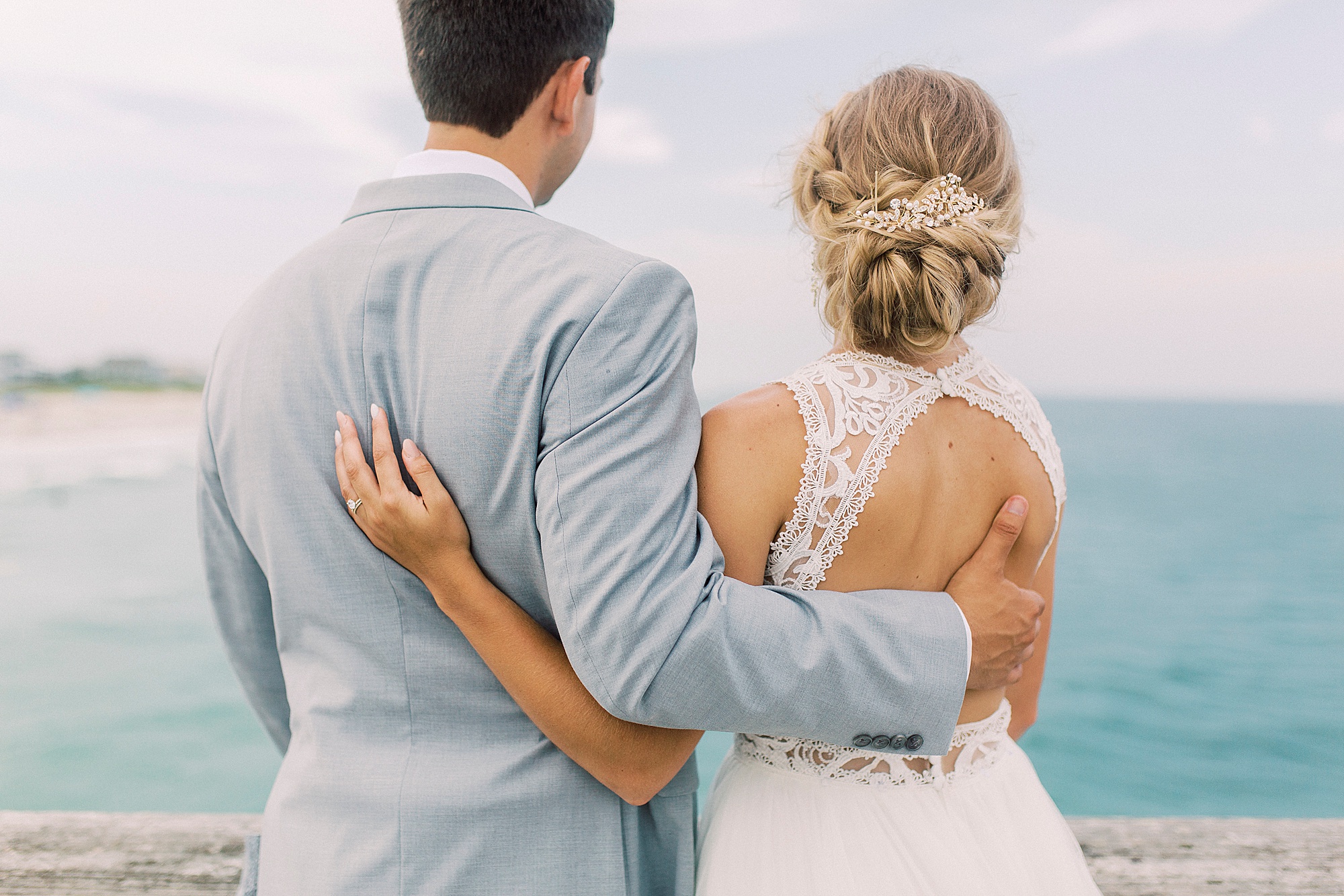 bride hugs groom looking at water at Wrightsville Beach