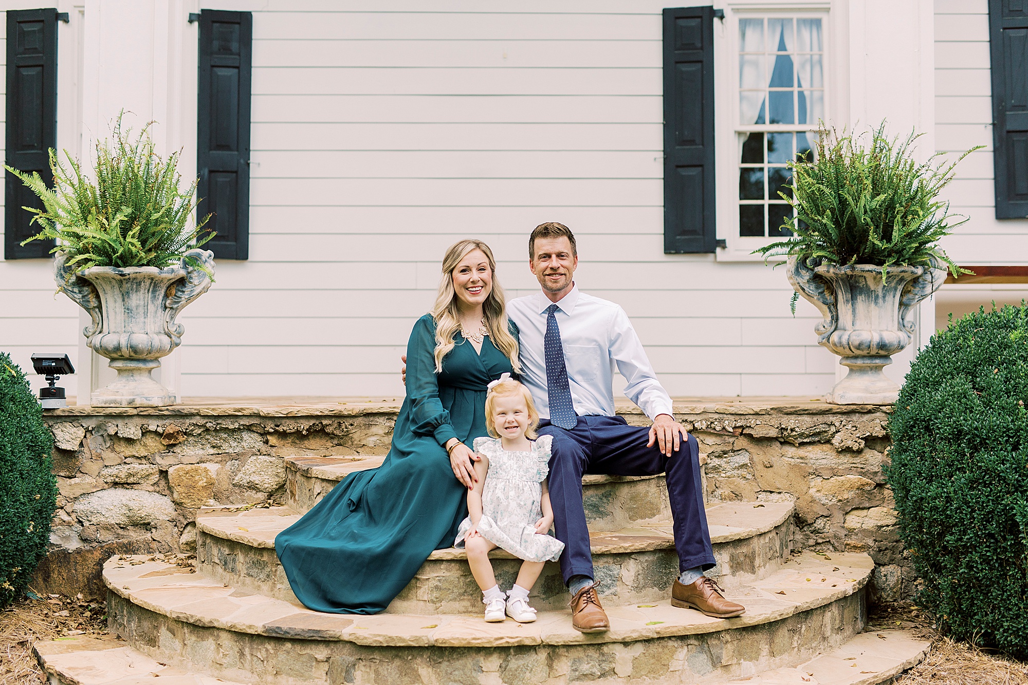 couple sits on steps at Vesuvius Vineyards with daughter