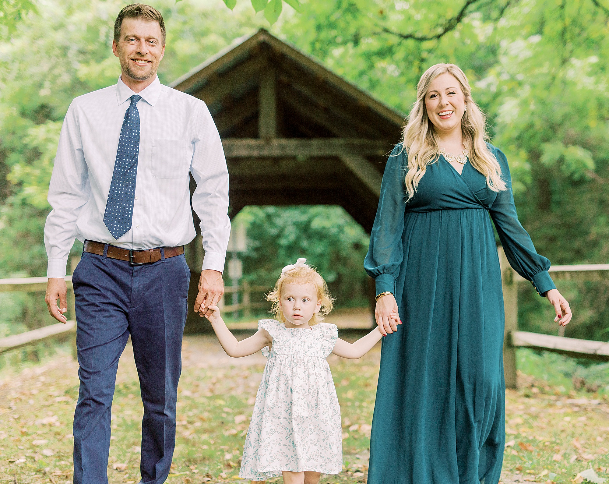 family of three walks by covered bridge in Vesuvius Vineyards