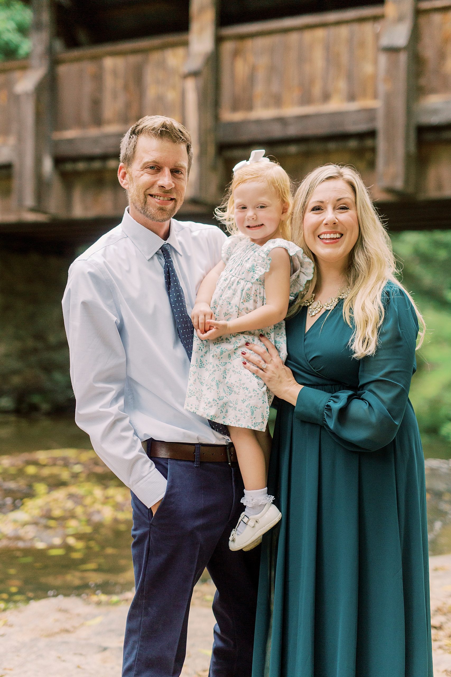 family of three poses by covered bridge near Vesuvius Vineyards