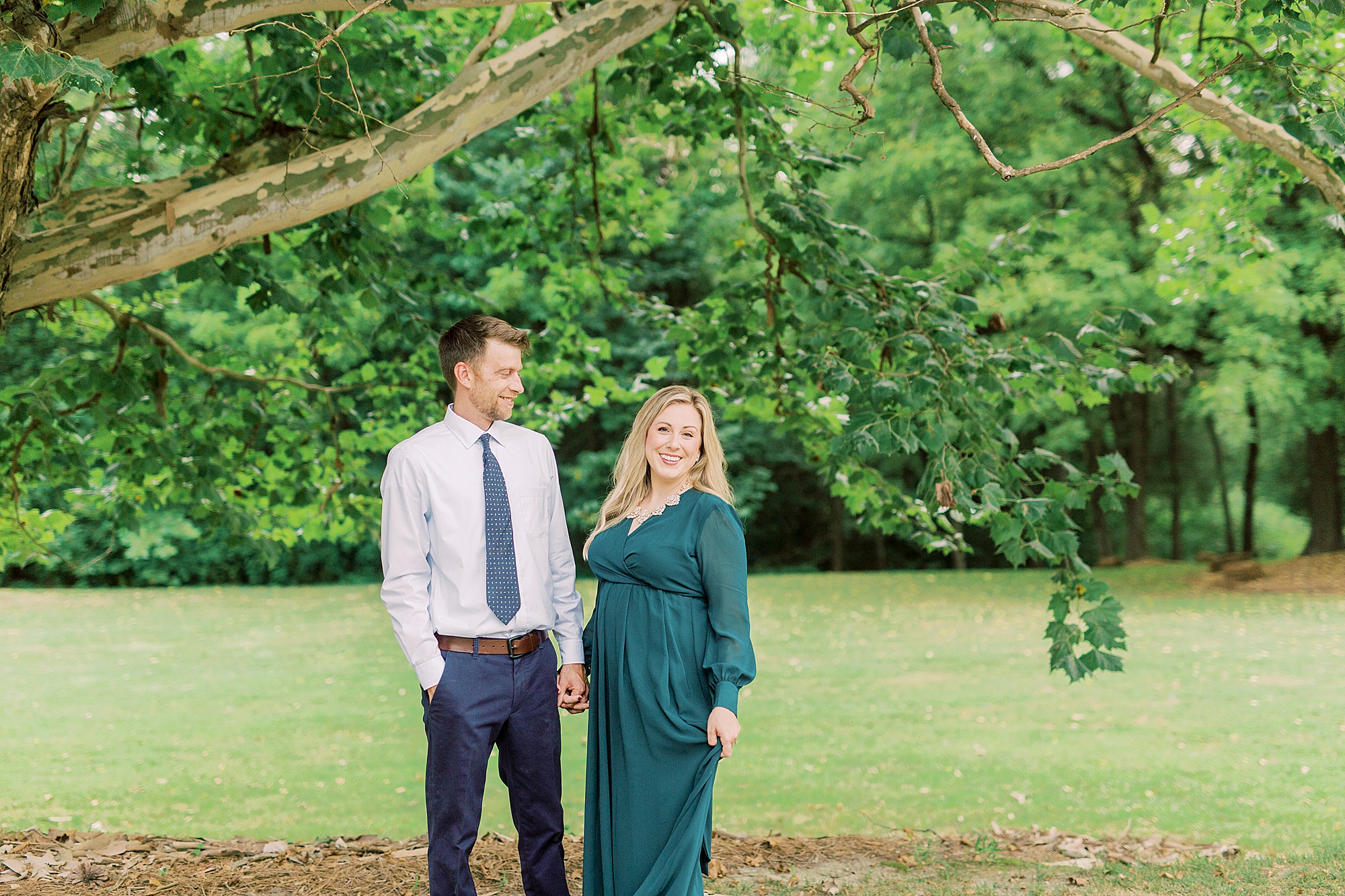 engaged couple poses under tree