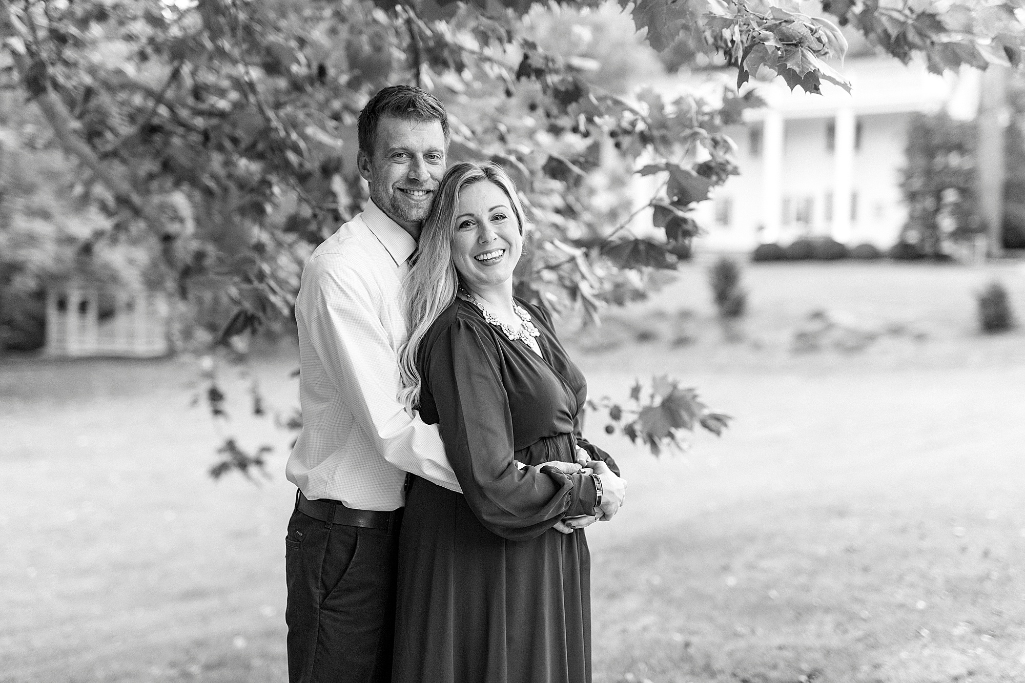 groom holds bride under tree