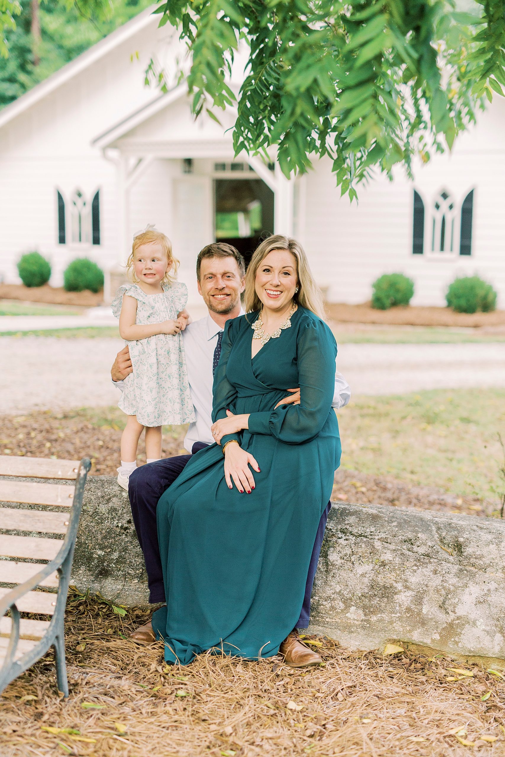family of three sits near stone wall at Vesuvius Vineyards
