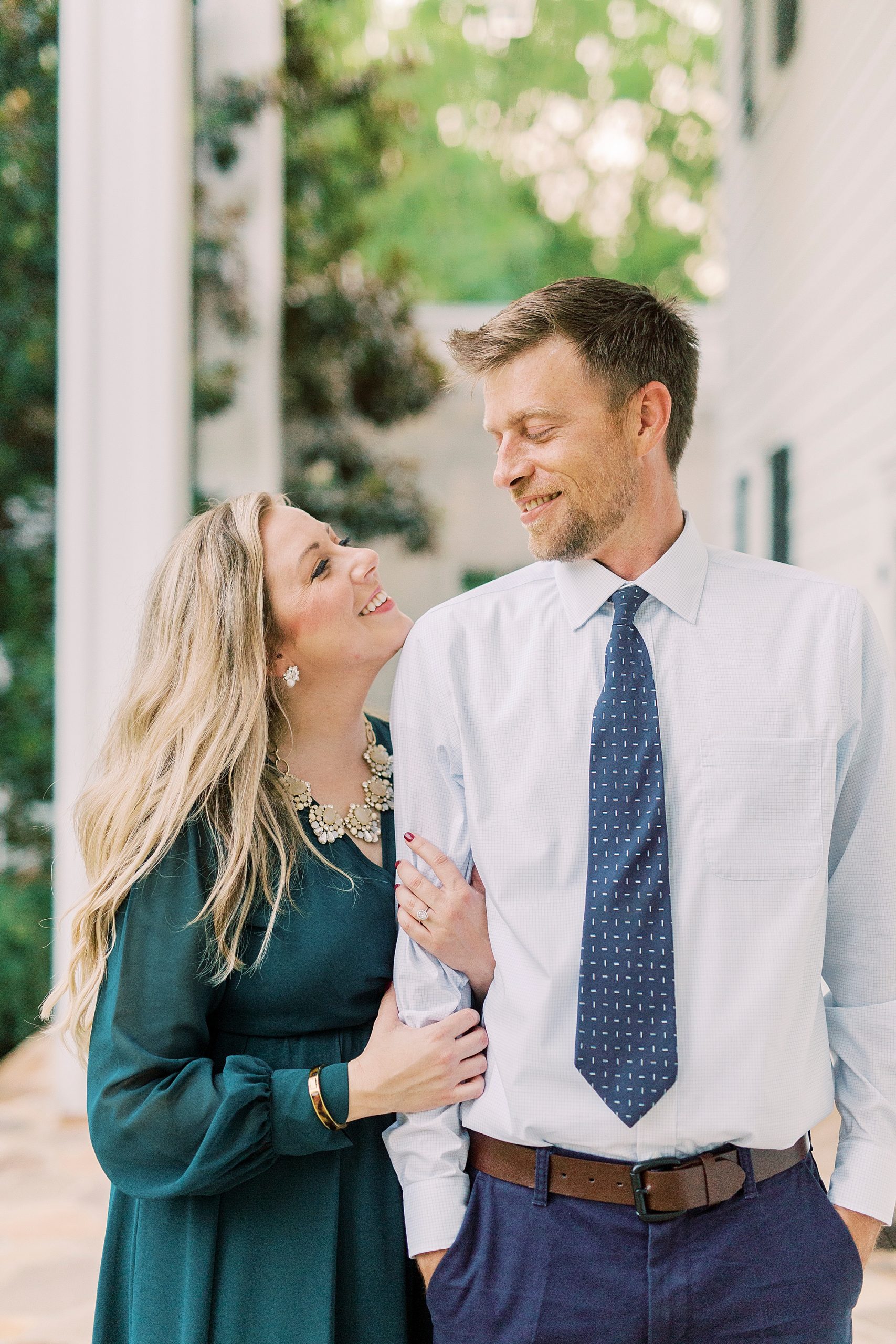 bride holds groom's arm and smiles up at him