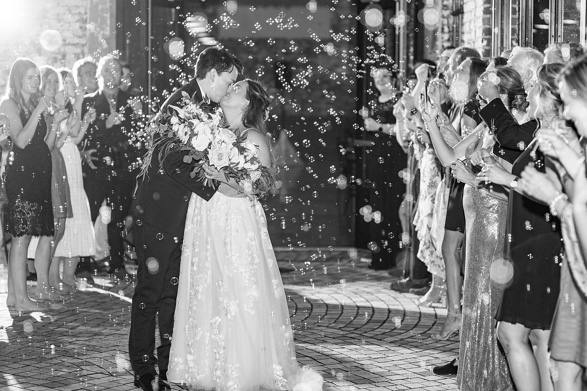 bride and groom kiss during bubble exit from the Cadillac Service Garage