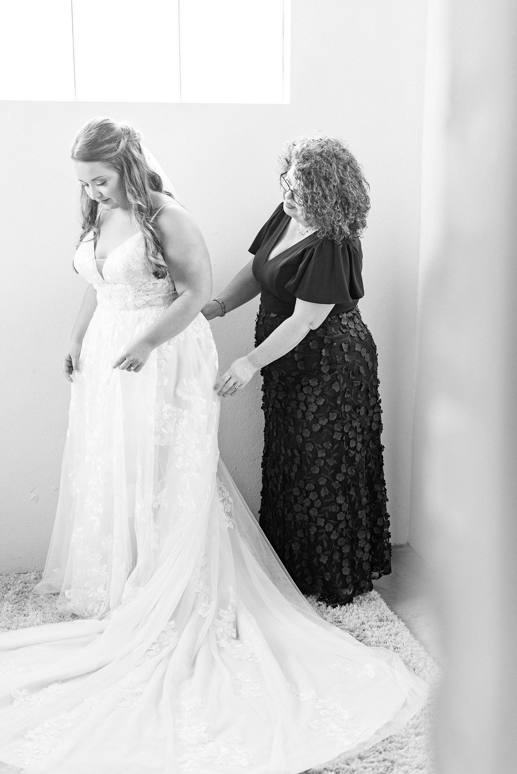 mother helps bride with veil on wedding morning
