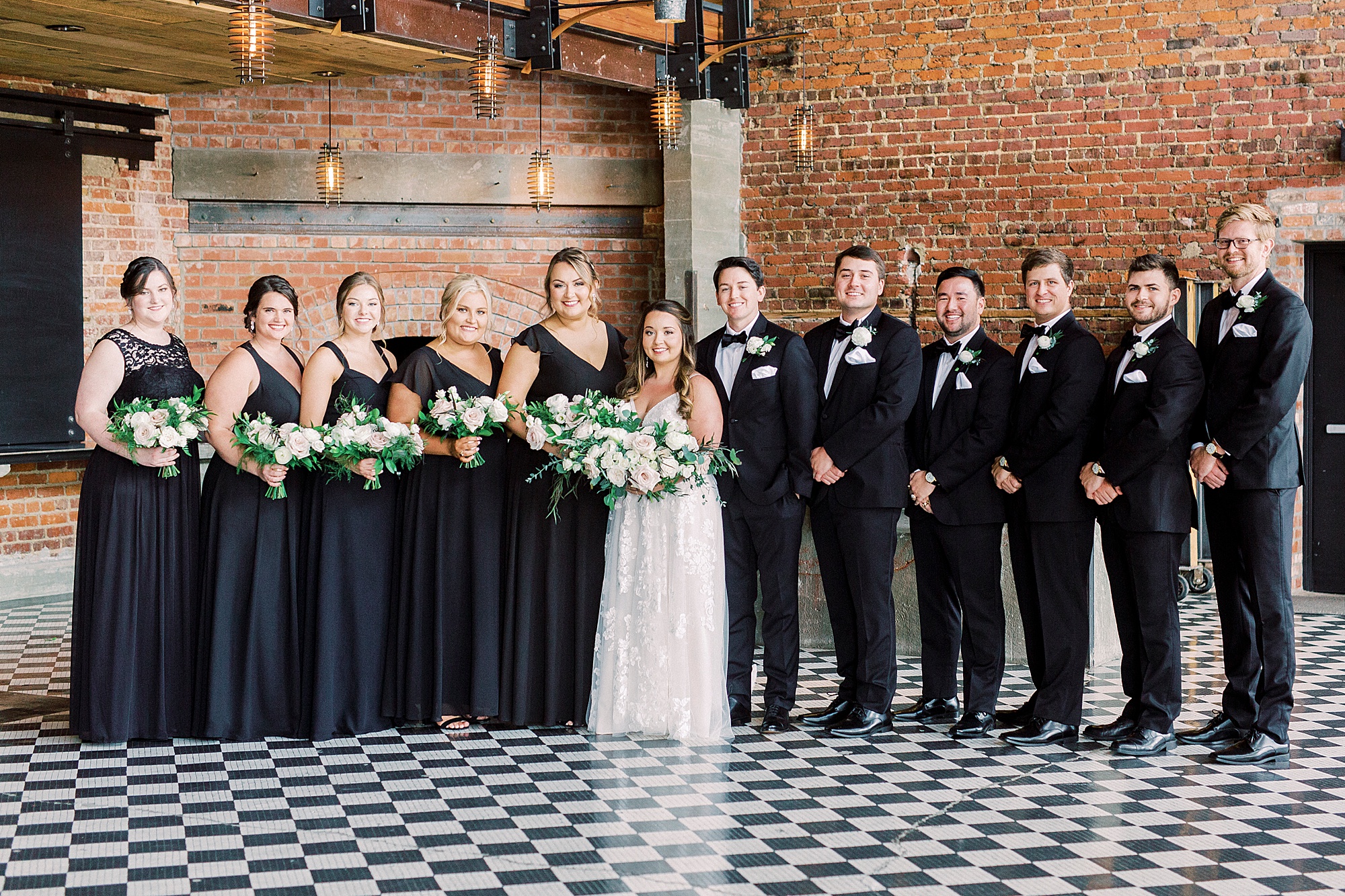 bride and groom pose with wedding party inside Cadillac Service Garage