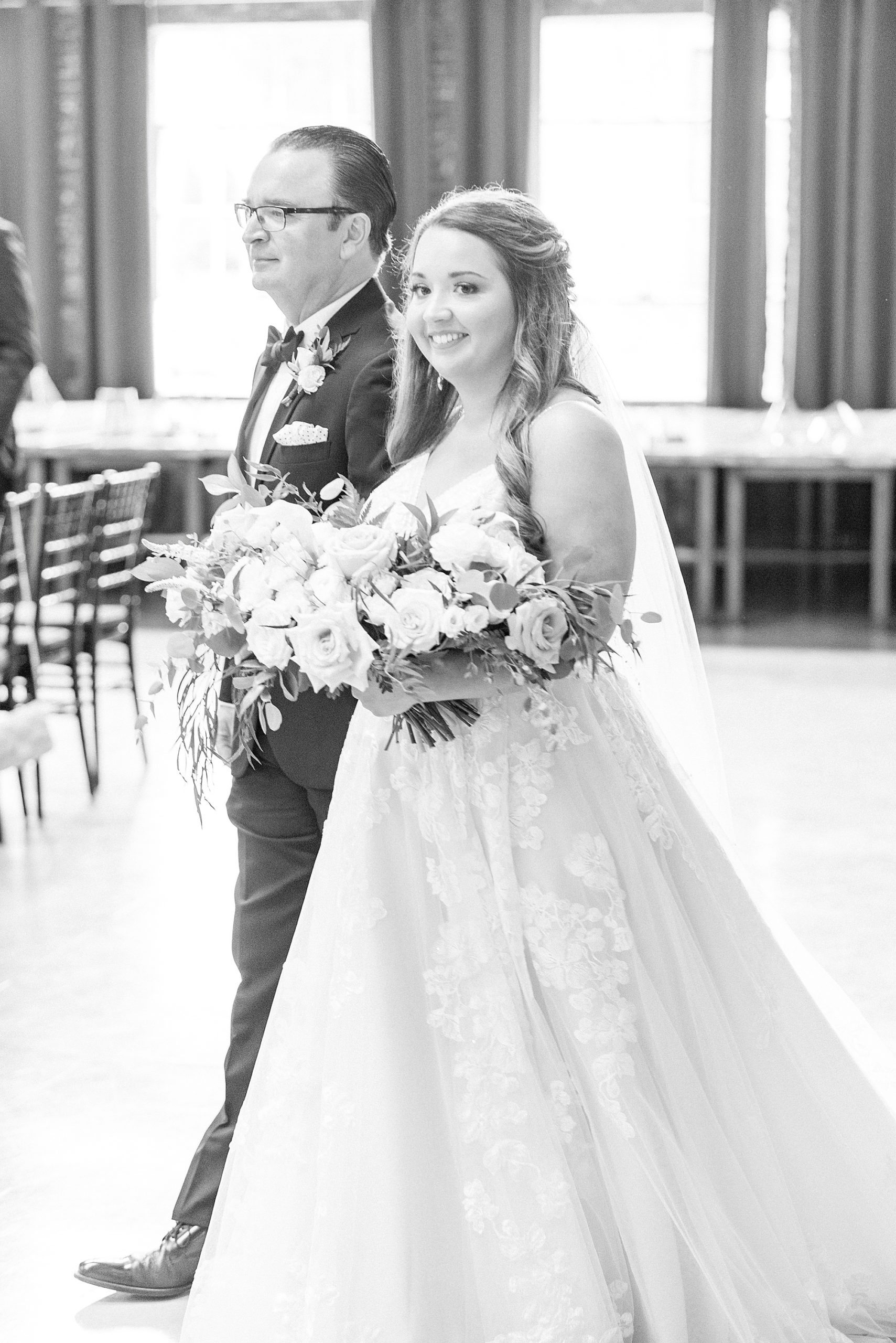 bride walks down aisle during ceremony at the Cadillac Service Garage