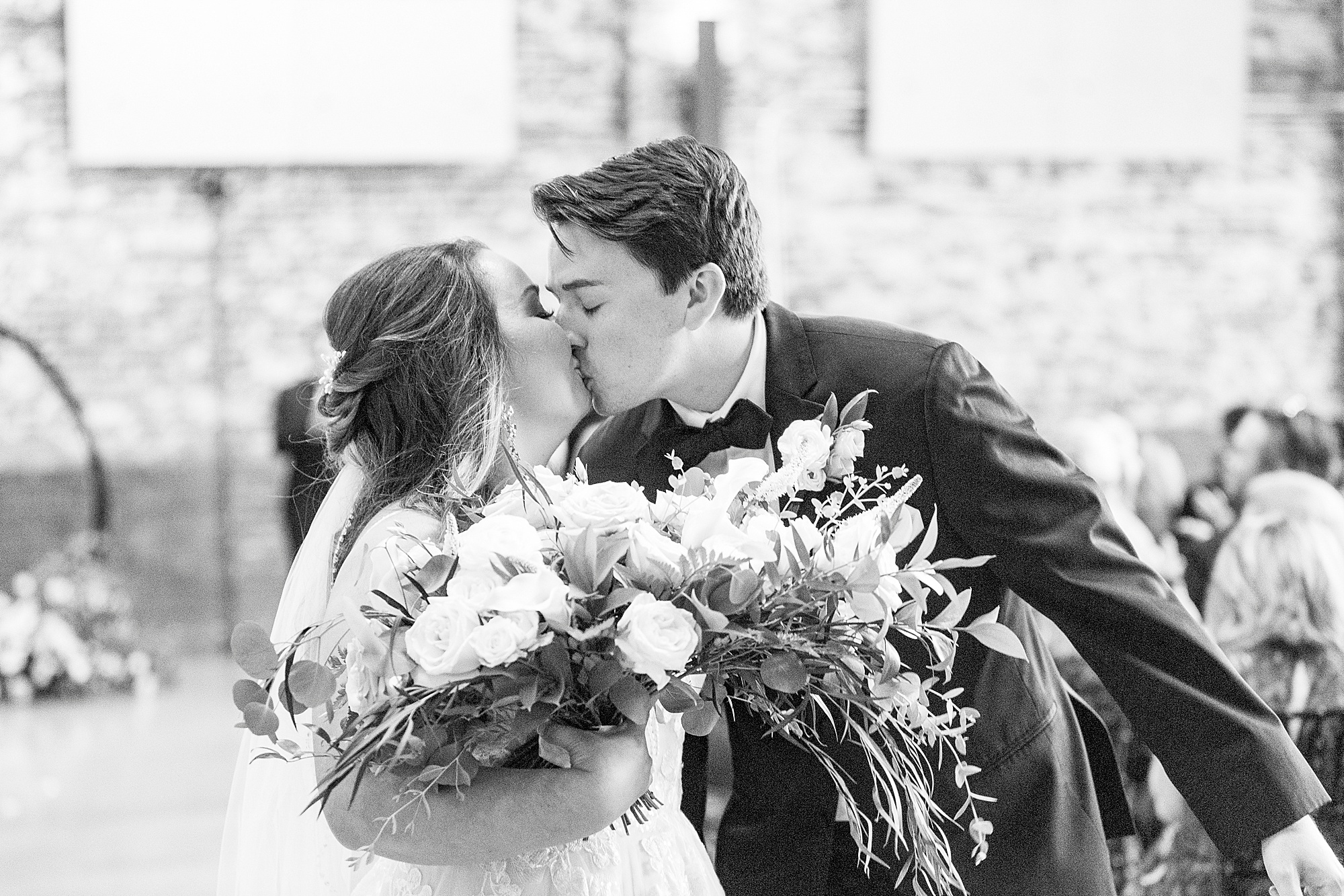 bride and groom kiss in aisle at the Cadillac Service Garage
