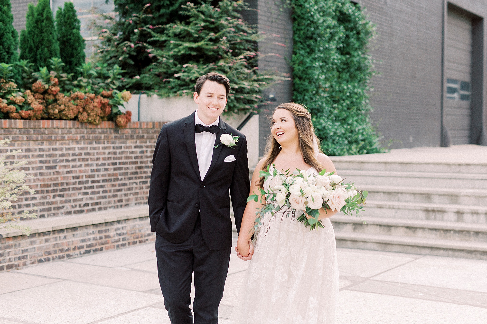 newlyweds hold hands walking through the Cadillac Service Garage