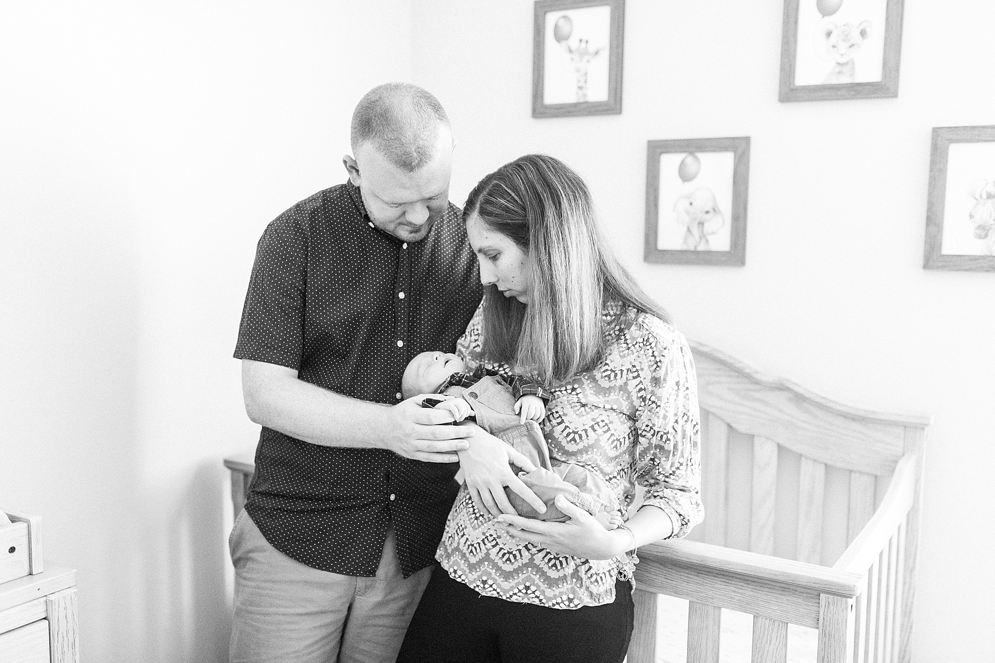 parents hold baby boy by crib during newborn photos at home