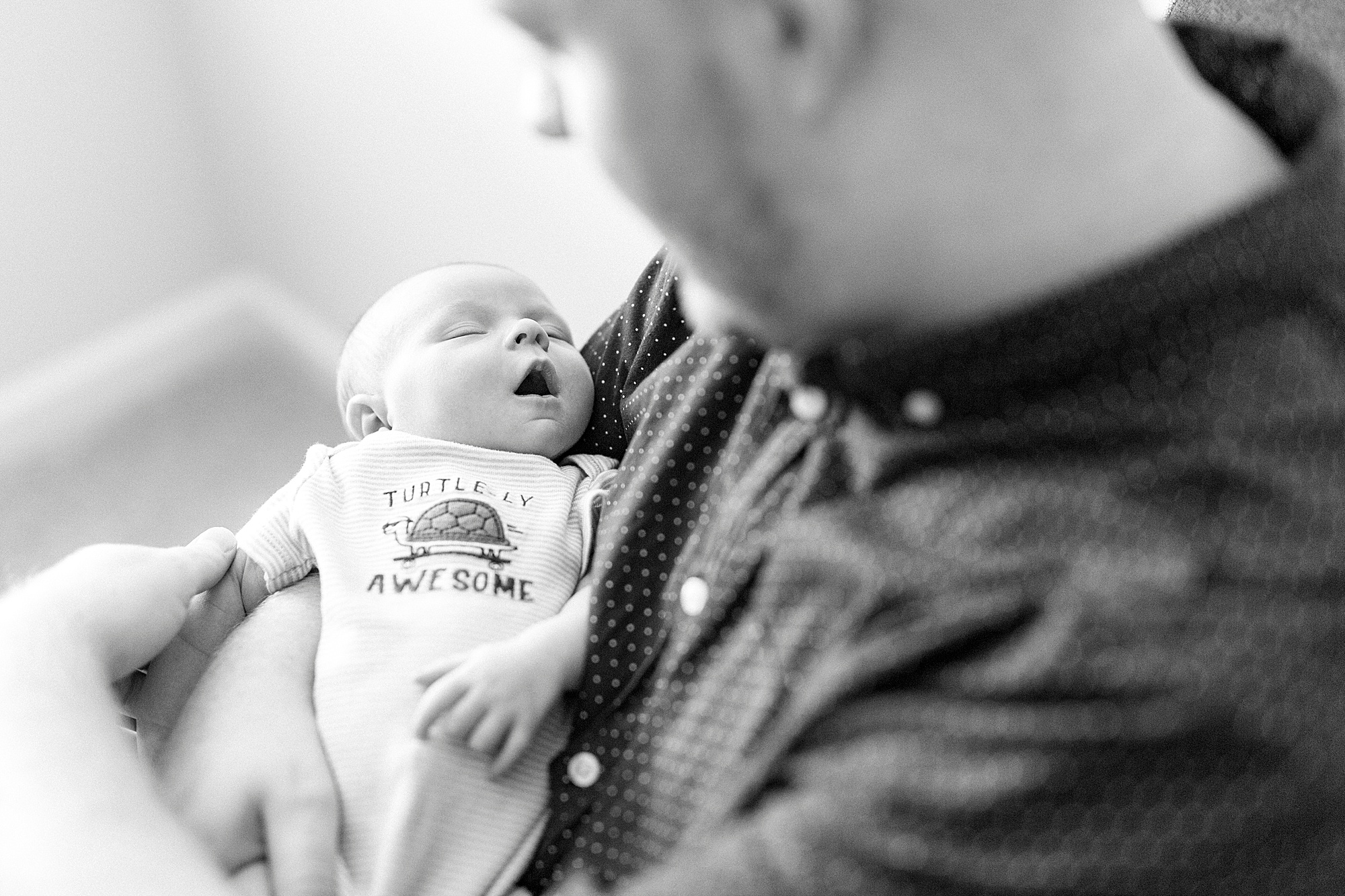 dad holds son looking down at hime during newborn session