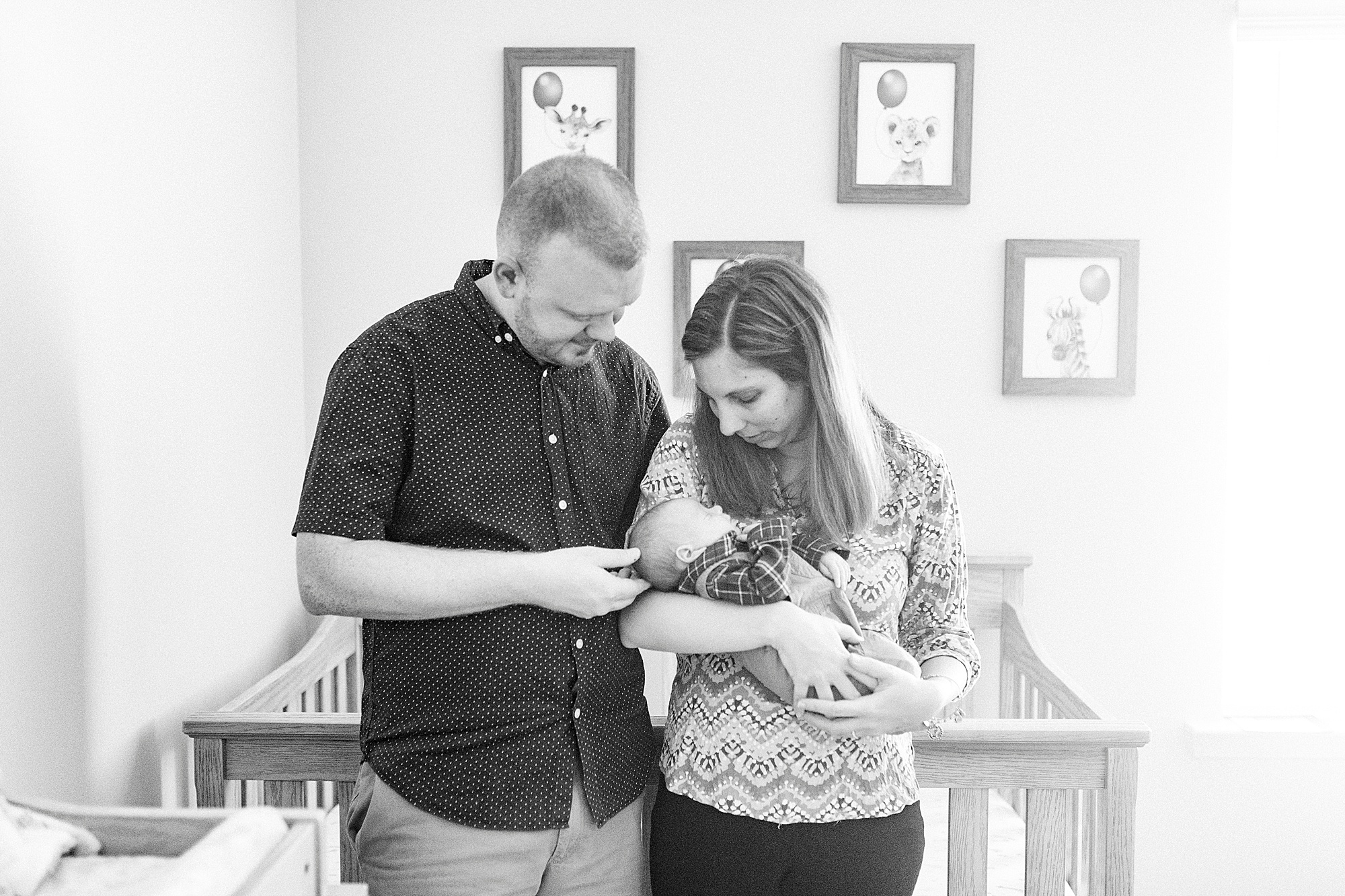 family of three poses by crib during lifestyle newborn session