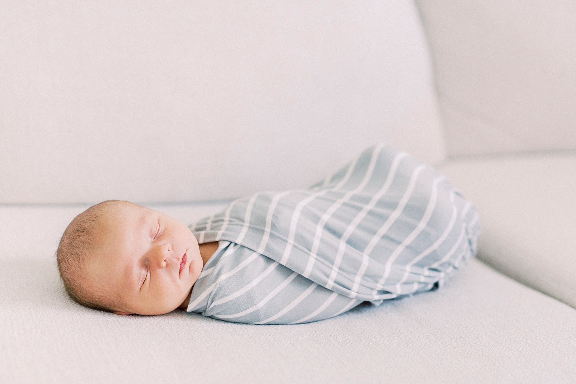 baby sleeps in blue swaddle during lifestyle newborn session