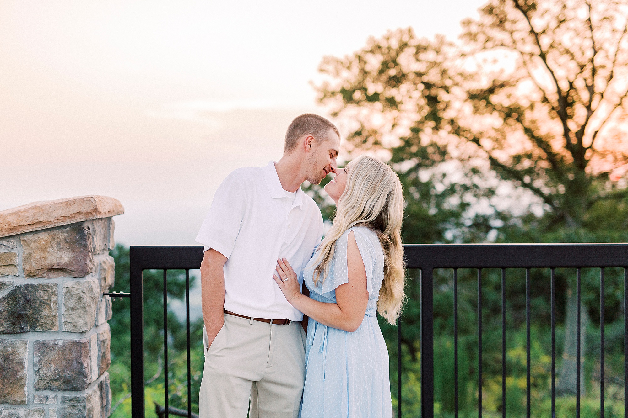 engaged couple kisses on mountain overlook